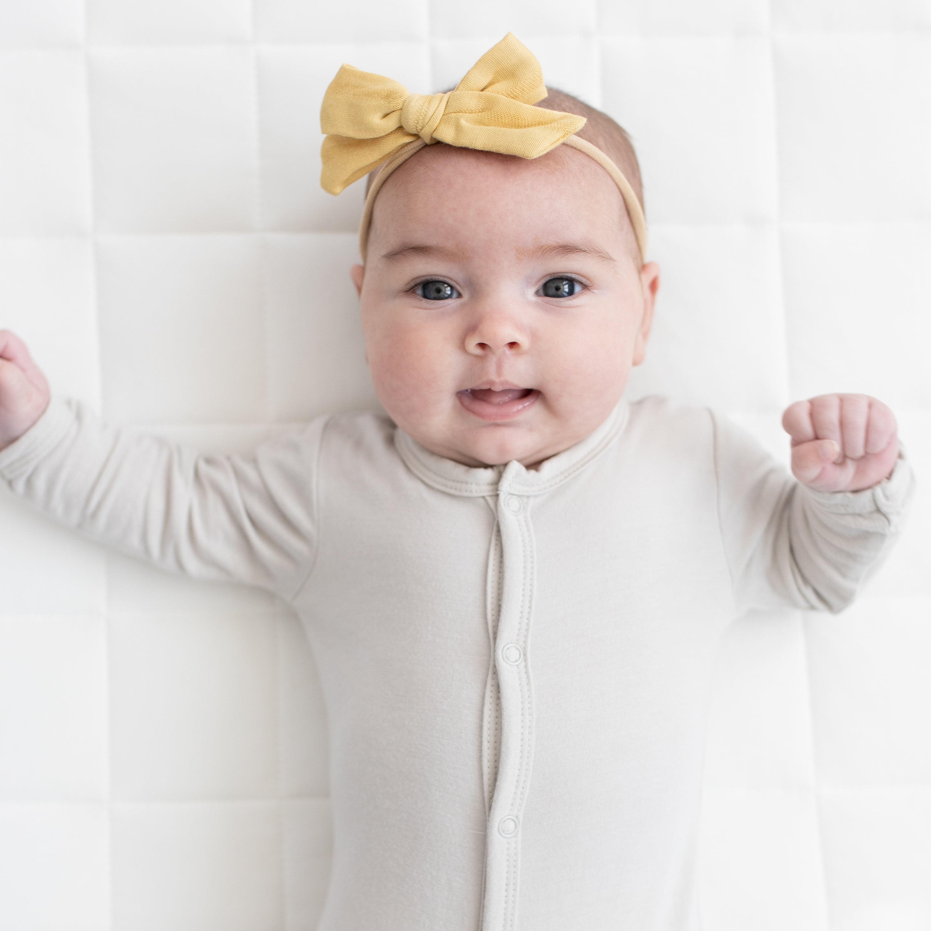 Baby wearing Medium Bamboo Muslin Bow in Sandcastle