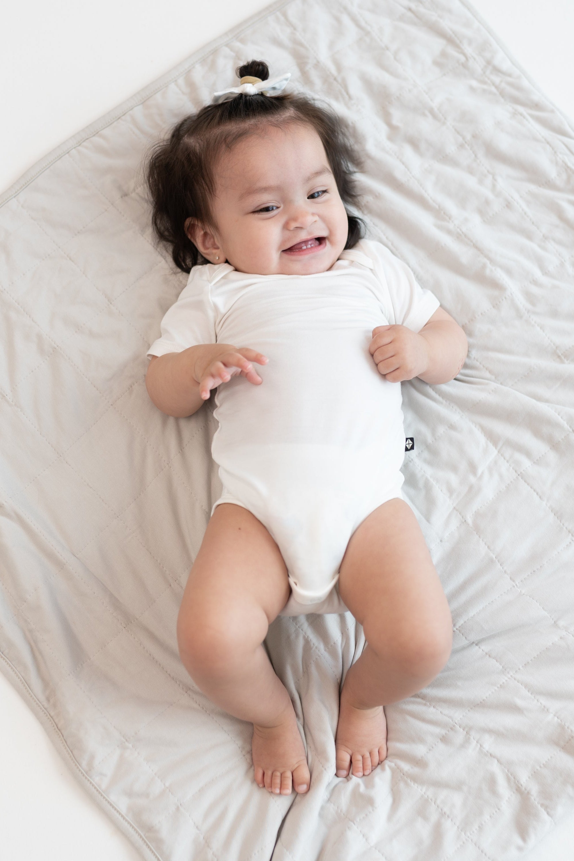 Baby in cloud bodysuit laying on Baby Blanket in Oat 1.0