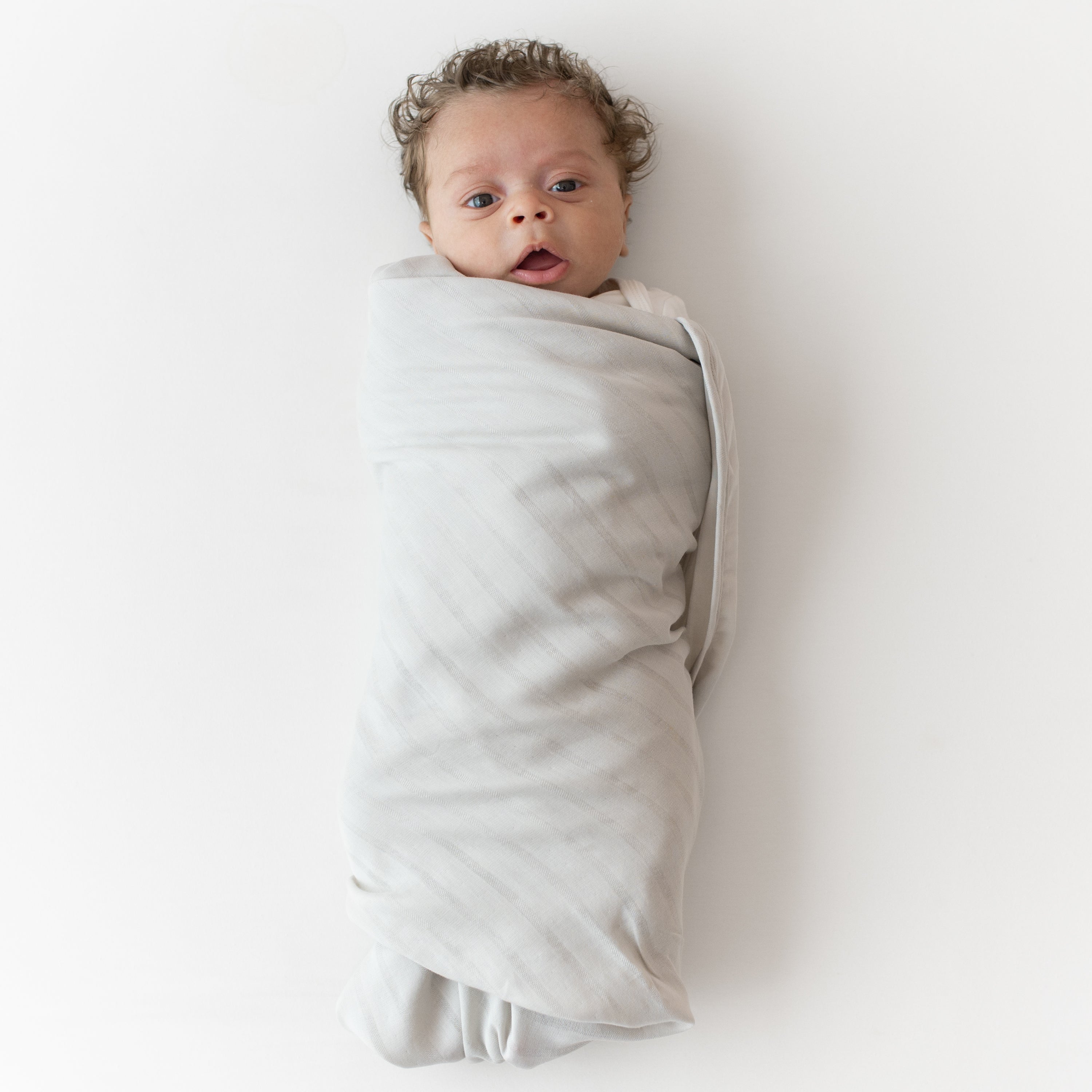 Baby wrapped in Bamboo Muslin Swaddler Blanket in Oat