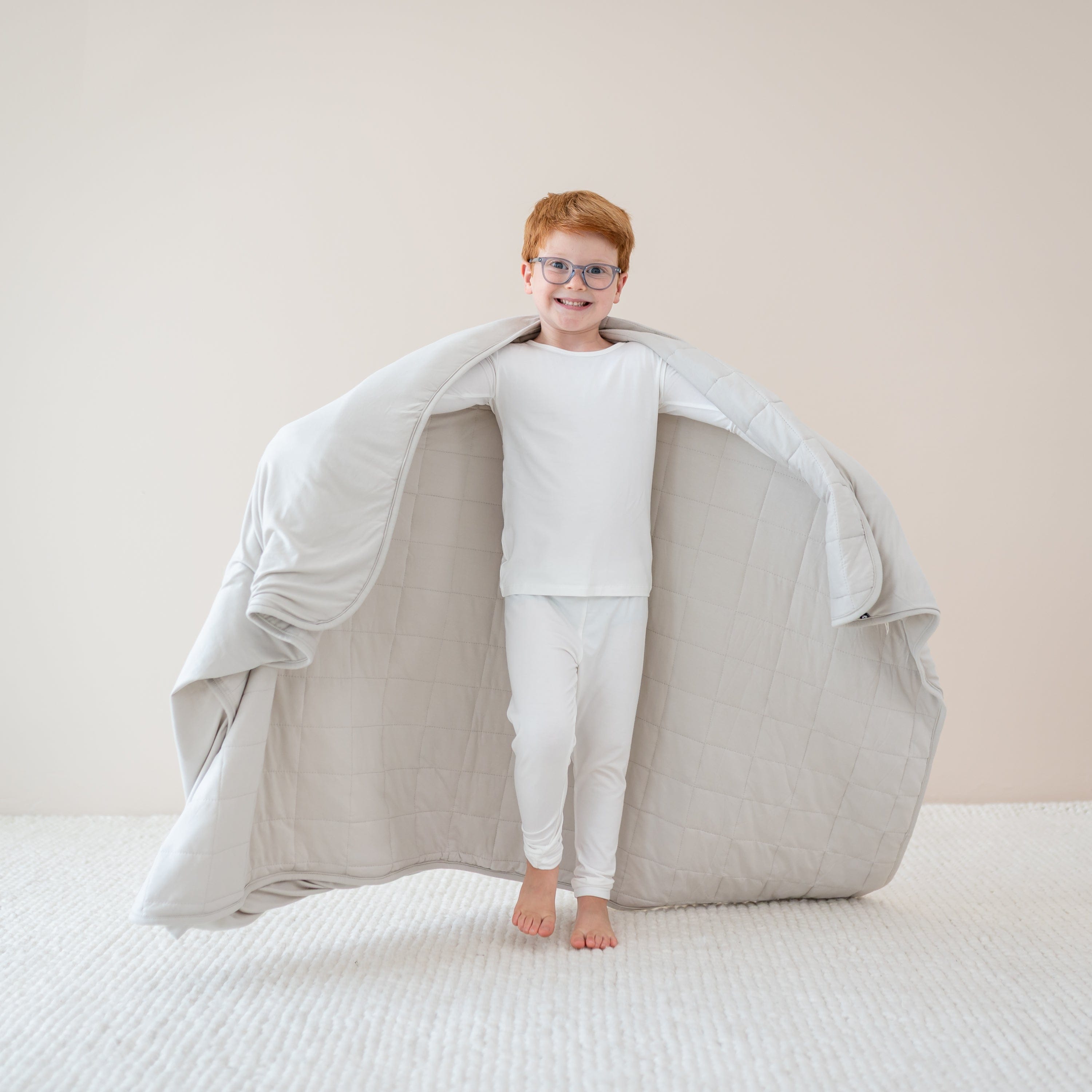 Child in cloud pajamas holding out in Youth Blanket in Oat 1.0