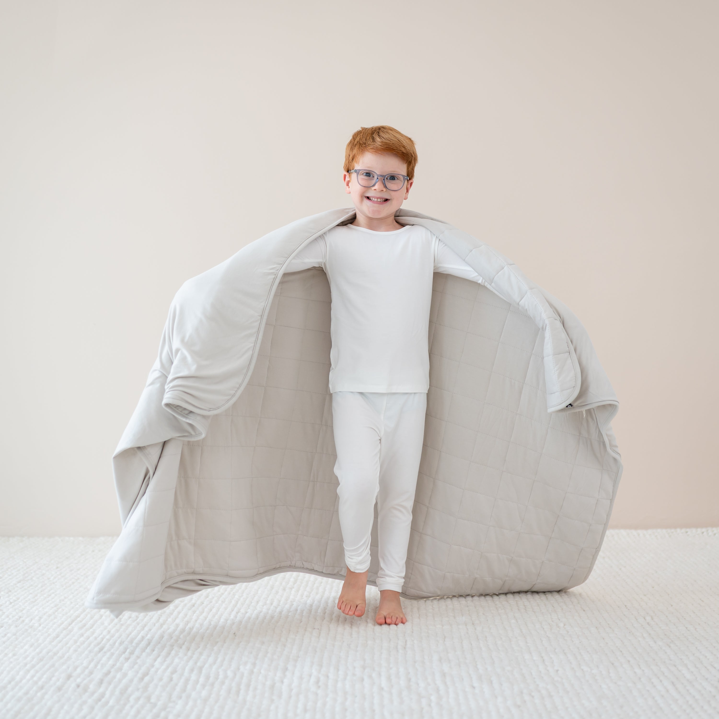 Child in cloud pajamas holding out in Youth Blanket in Oat 1.0