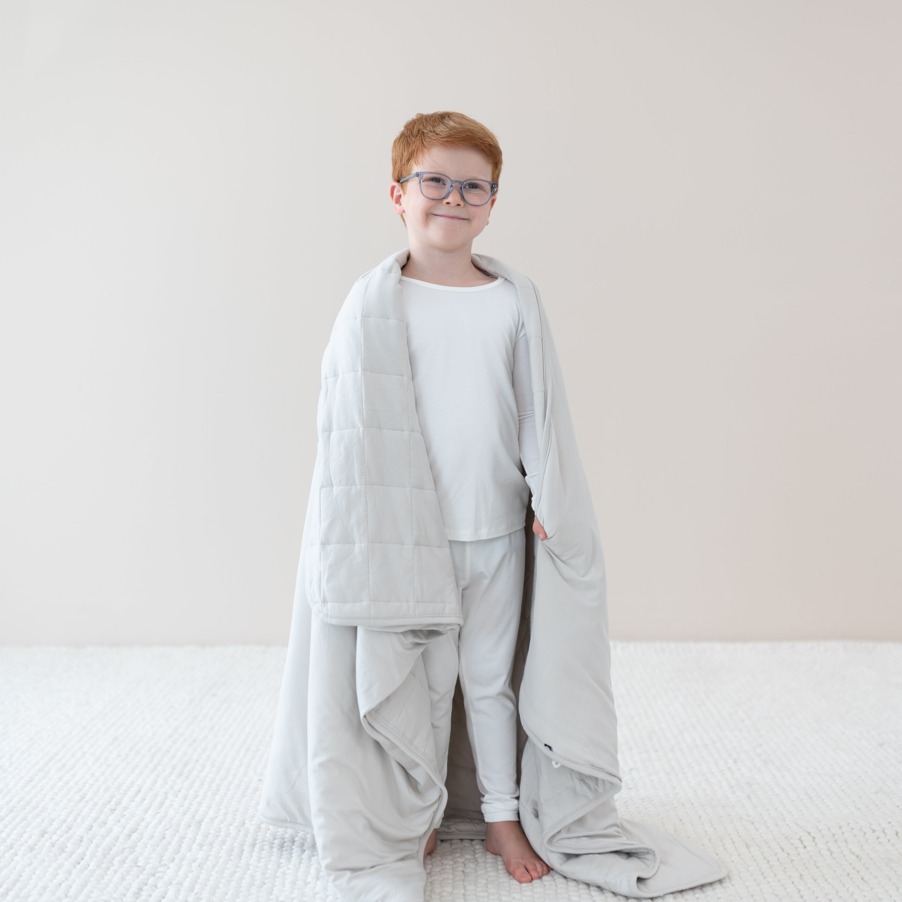 Child in cloud pajamas wrapped in Youth Blanket in Oat 1.0