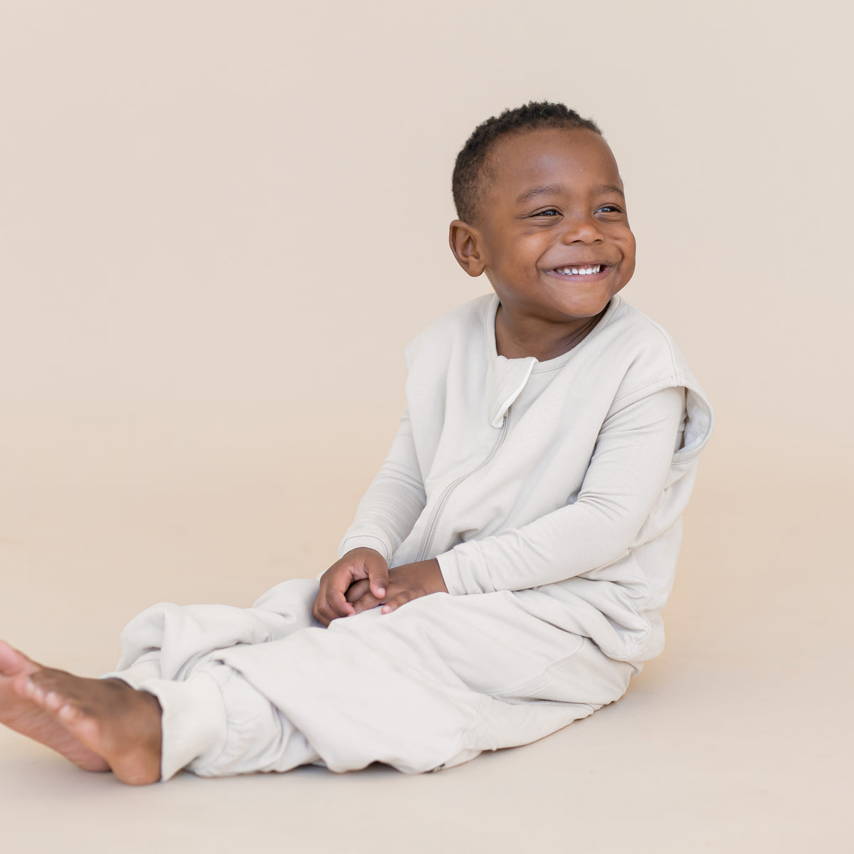 Young boy wearing sleep bag walker in a creamy off white color