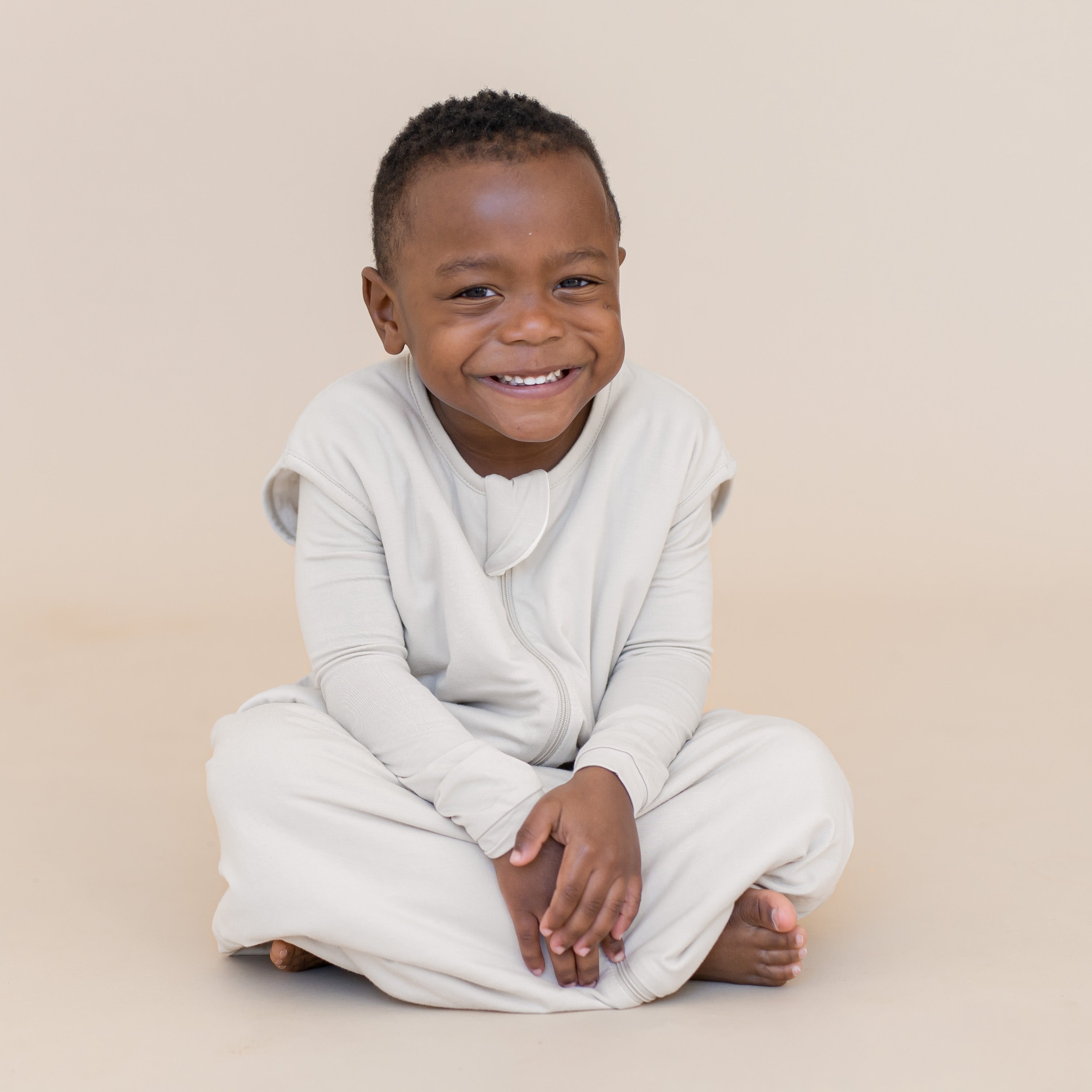 Young boy wearing sleep bag walker in a creamy off white color