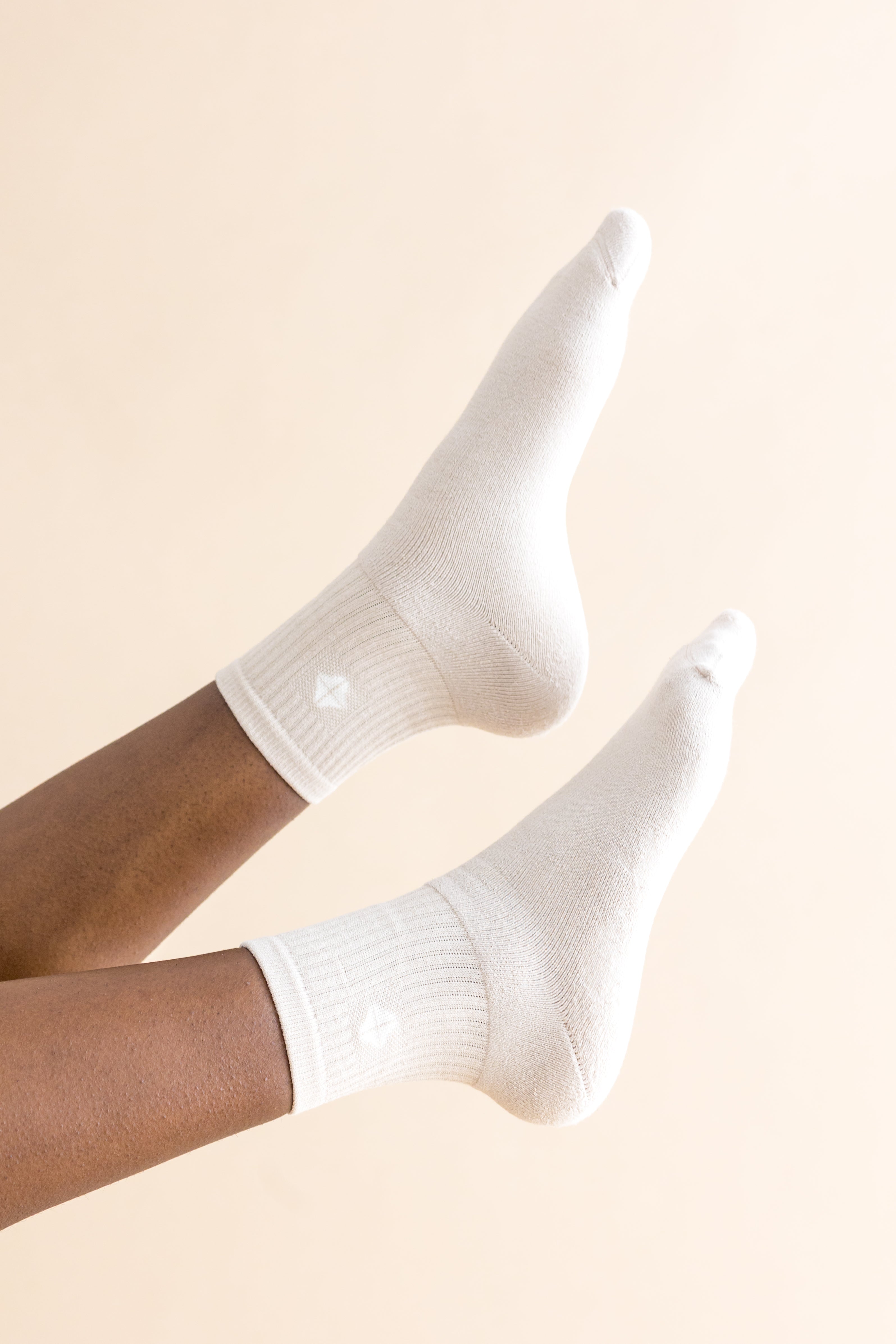 Adult Crew Socks in Oat shown on a models feet in the air in front of a cream colored background