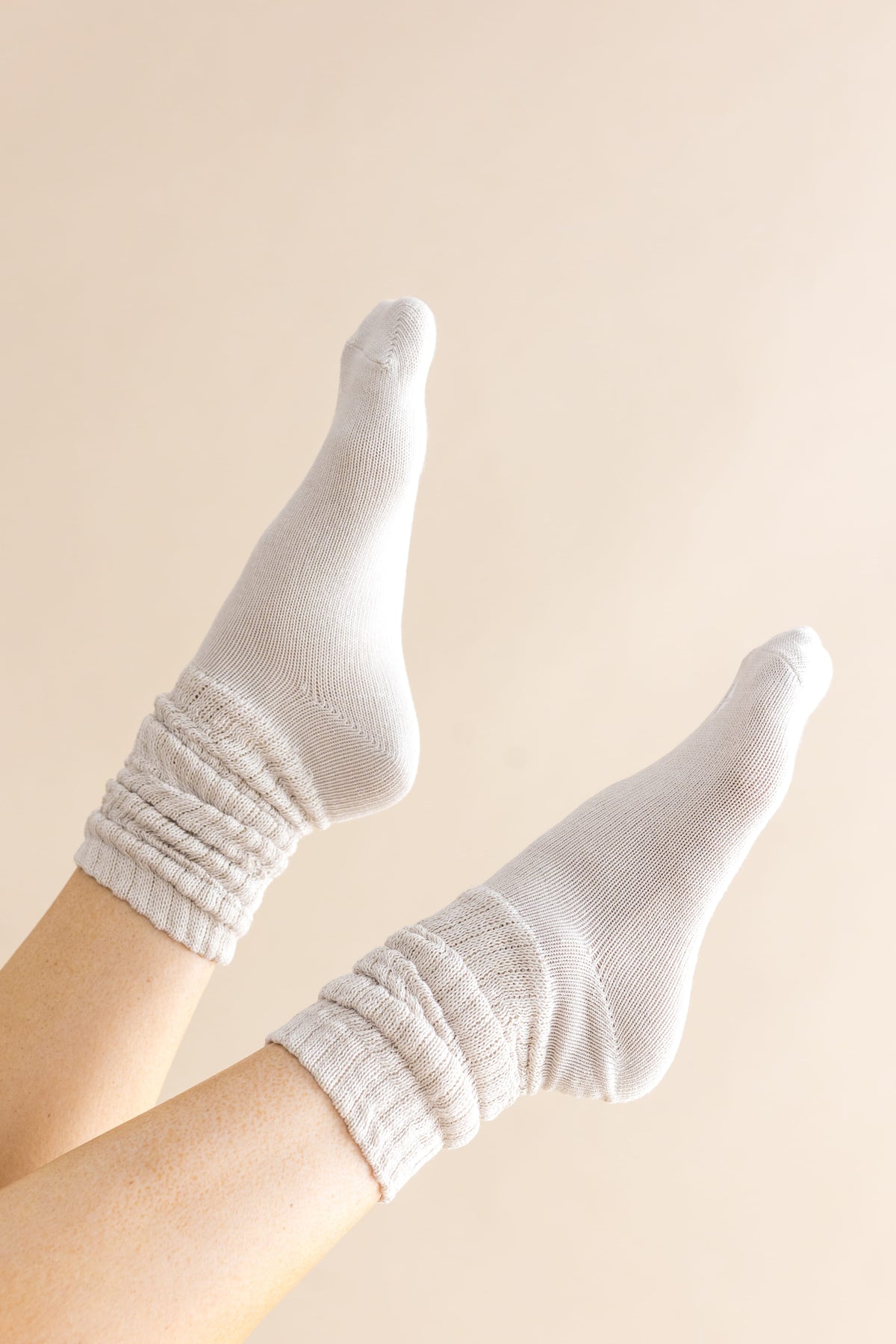 Adult Scrunch Socks in Oat shown on a models feet in the air in front of a cream colored background