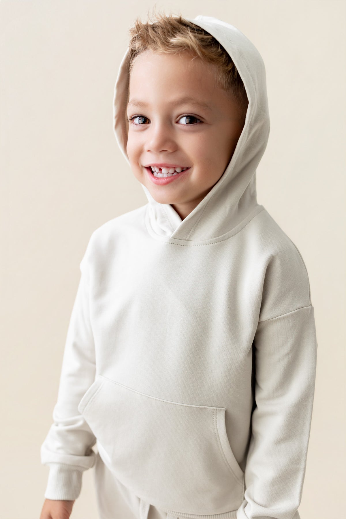 Boy wearing Hoodie in Oat color on a beige background