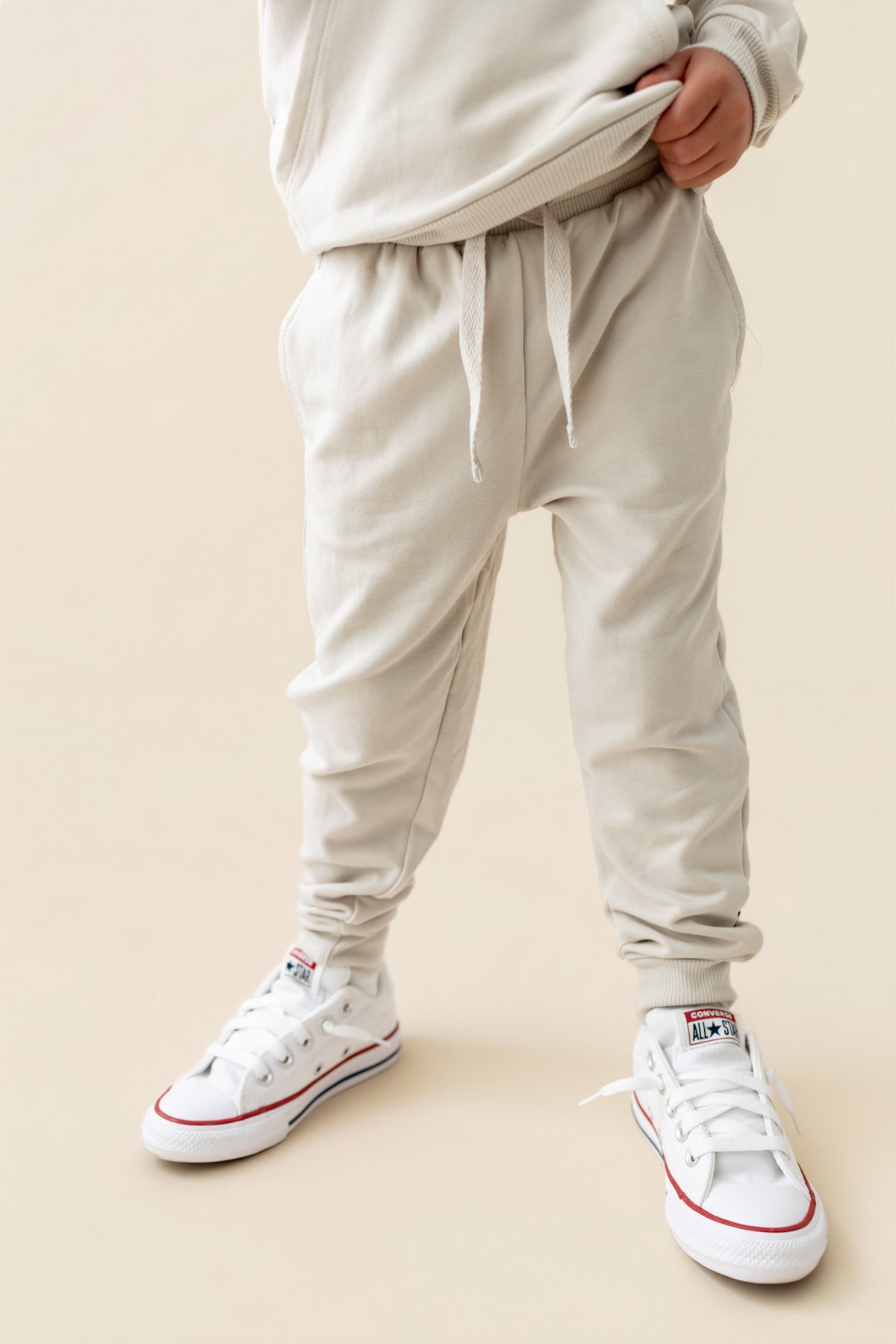 Modal wearing Jogger Pant in Oat color under similar color shirt on a beige background