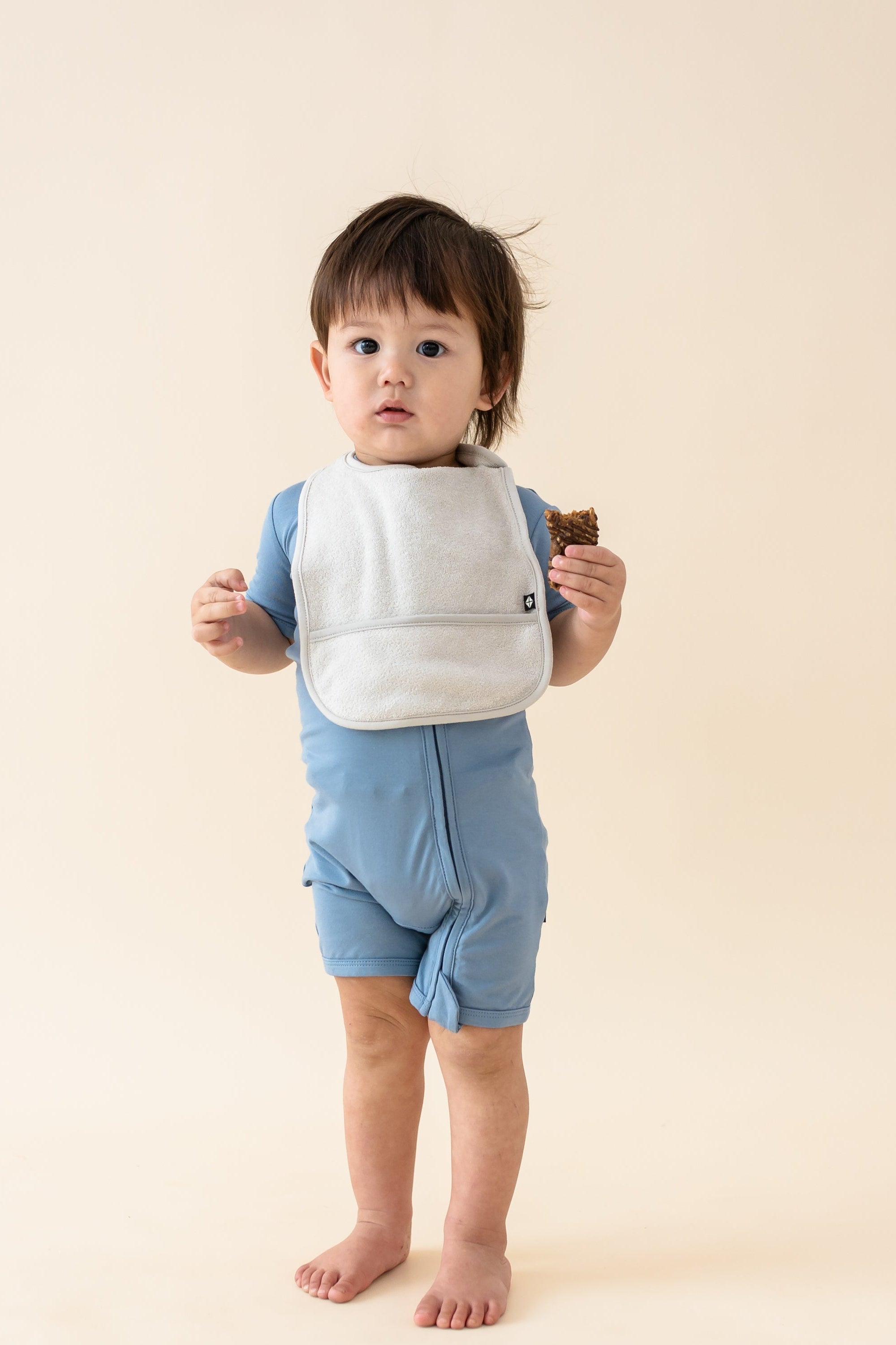 Toddler wearing Bamboo Terry Pocket Bib in Oat with Slate shortalls