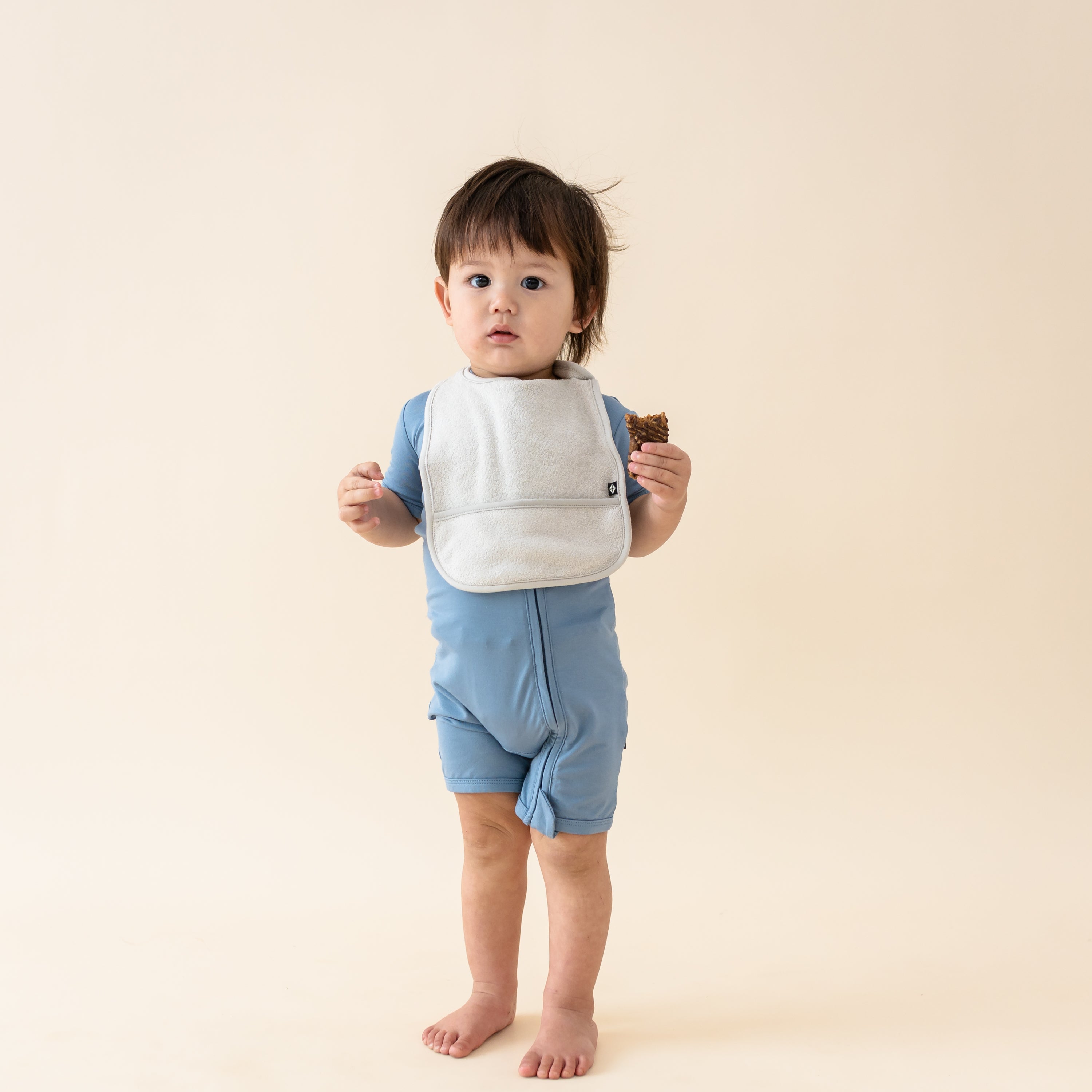 Toddler wearing Bamboo Terry Pocket Bib in Oat with Slate shortalls