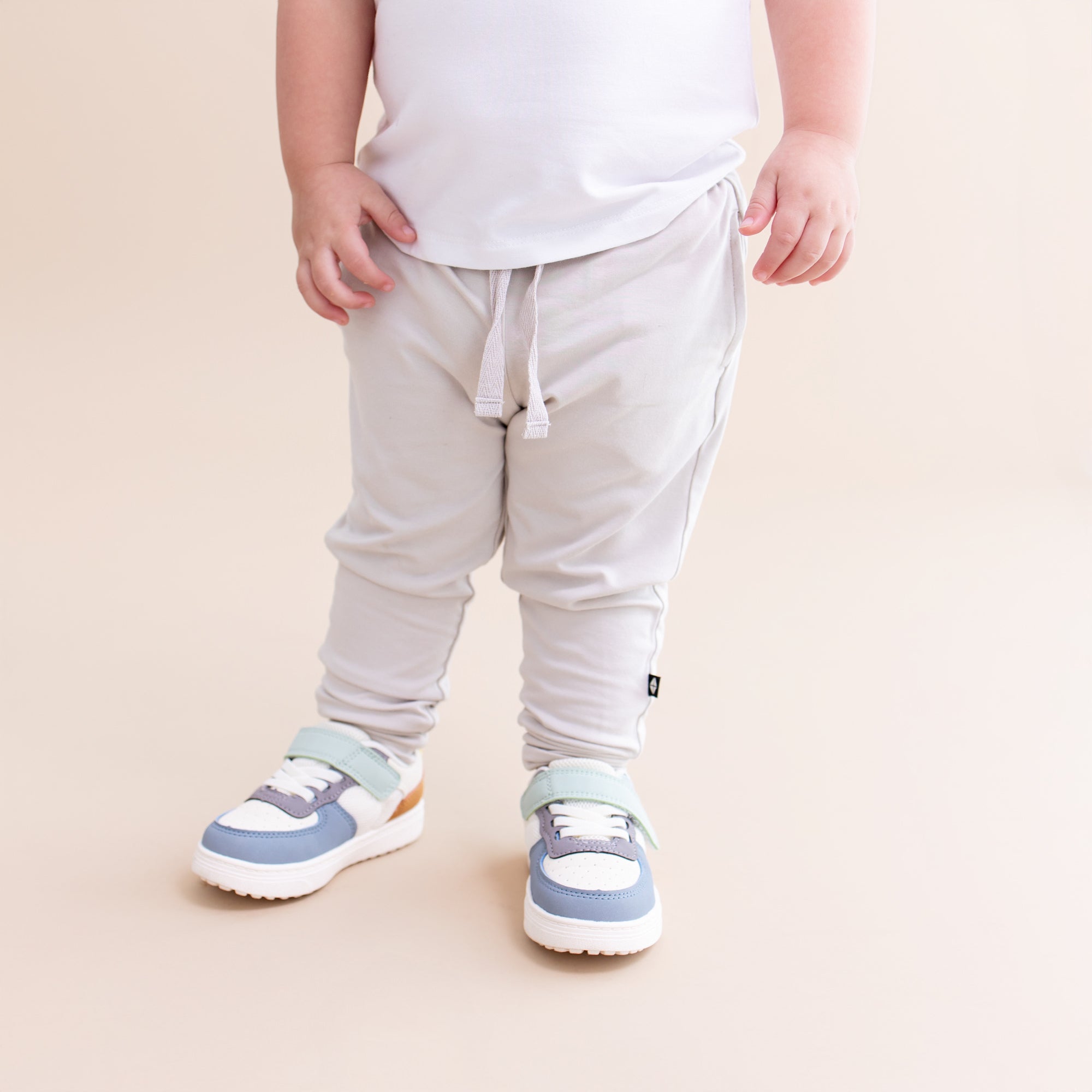 Close up of the Toddler Jogger Pant in Oat showing the black kyte baby tag logo on a toddler model