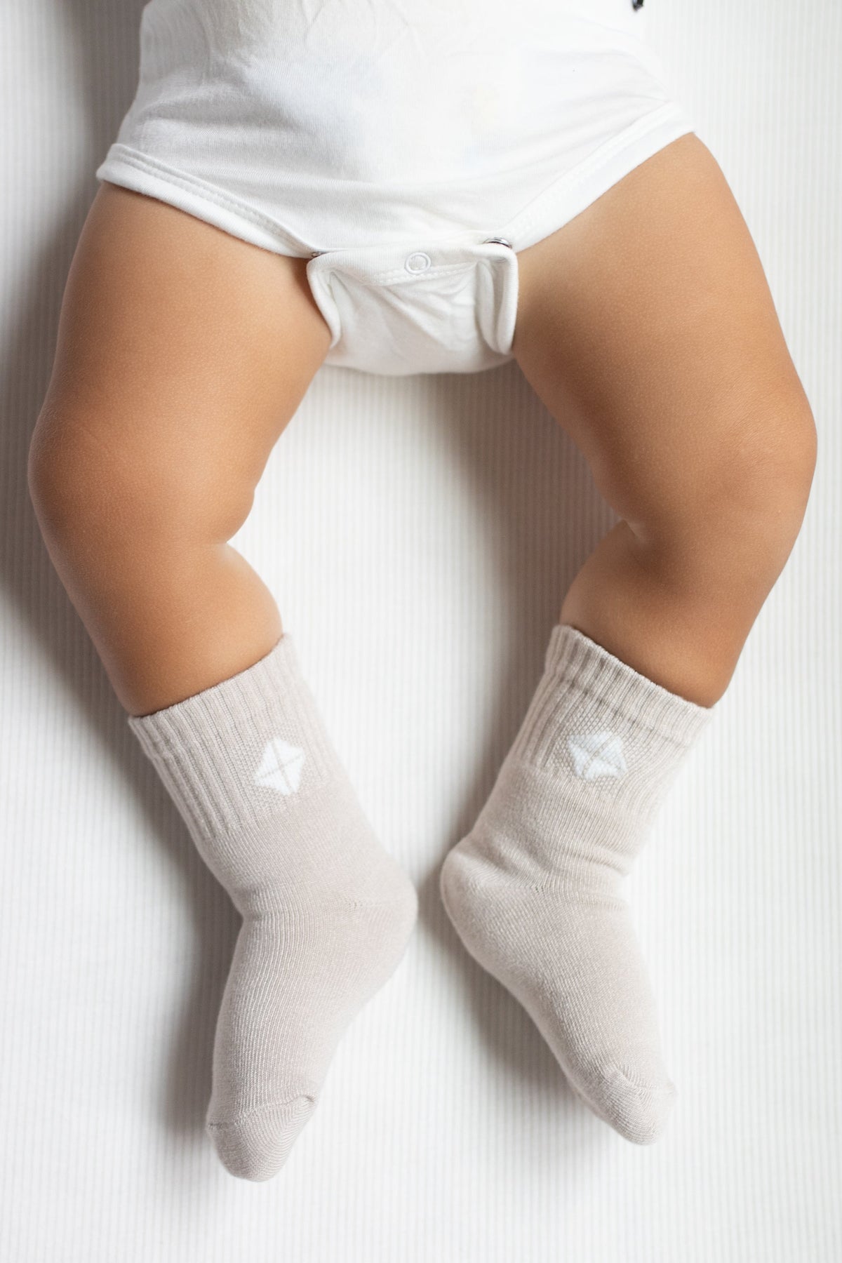 Crew Socks in Oat shown on an infant model with the Kyte Baby logo visible