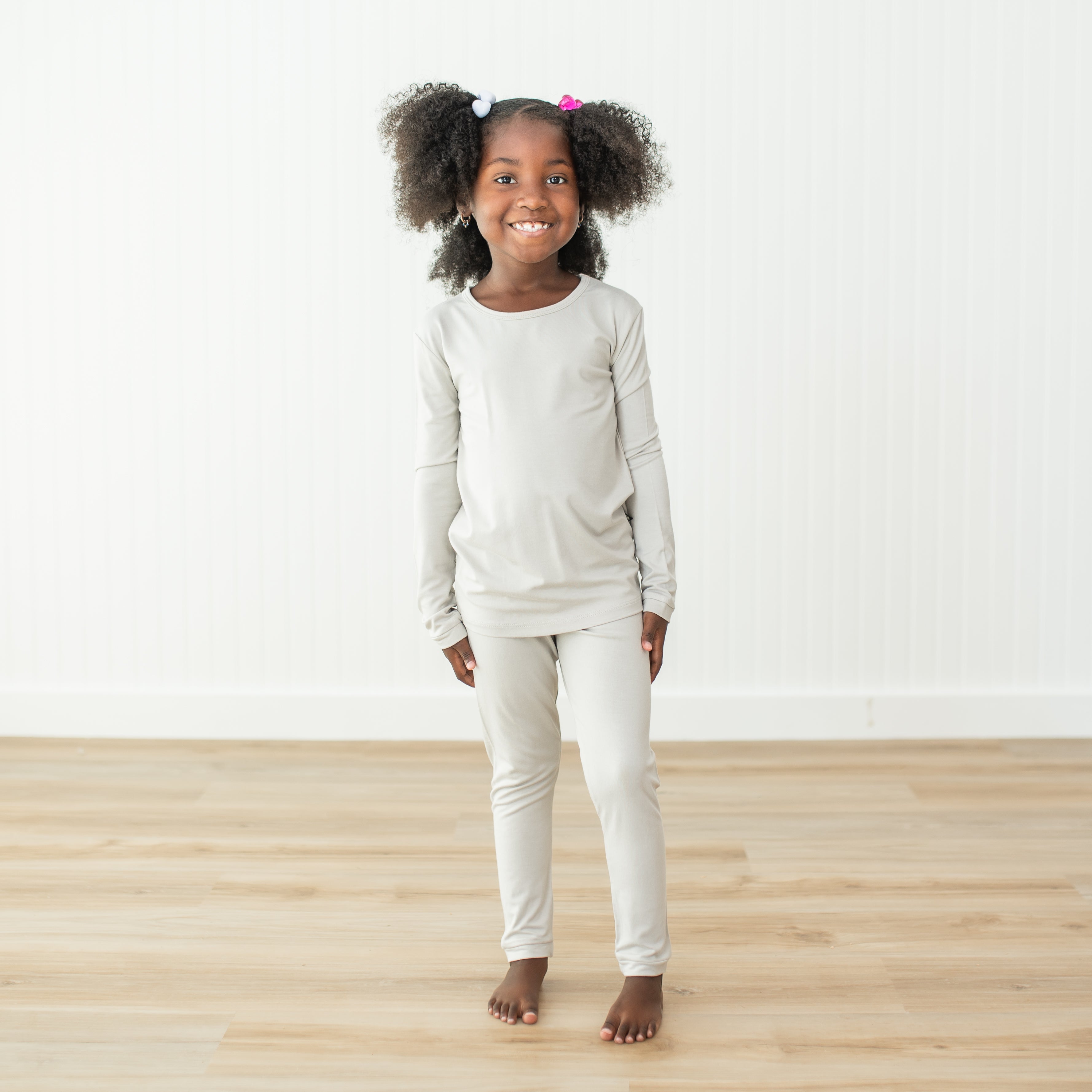 Toddler girl modeling long sleeve pajamas in a creamy light grey color