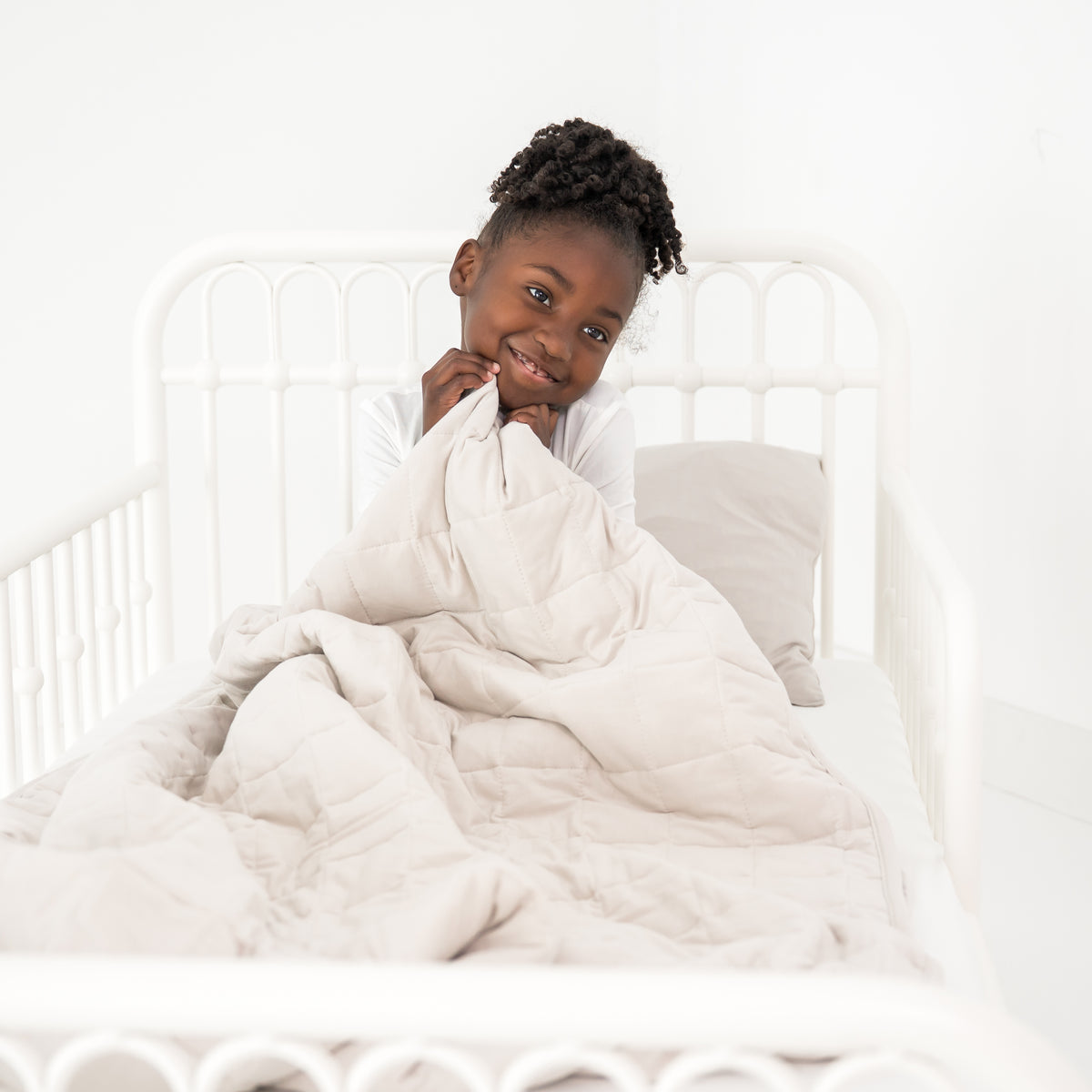 Child cozy in a toddler bed with a creamy off white blanket
