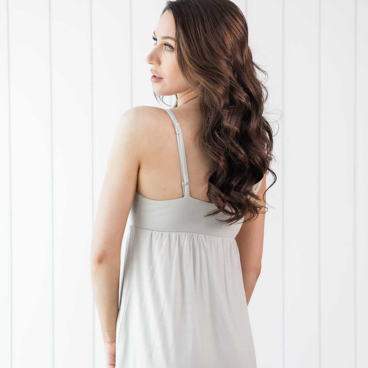 Woman wearing a light creamy grey nightgown showing the back of the dress
