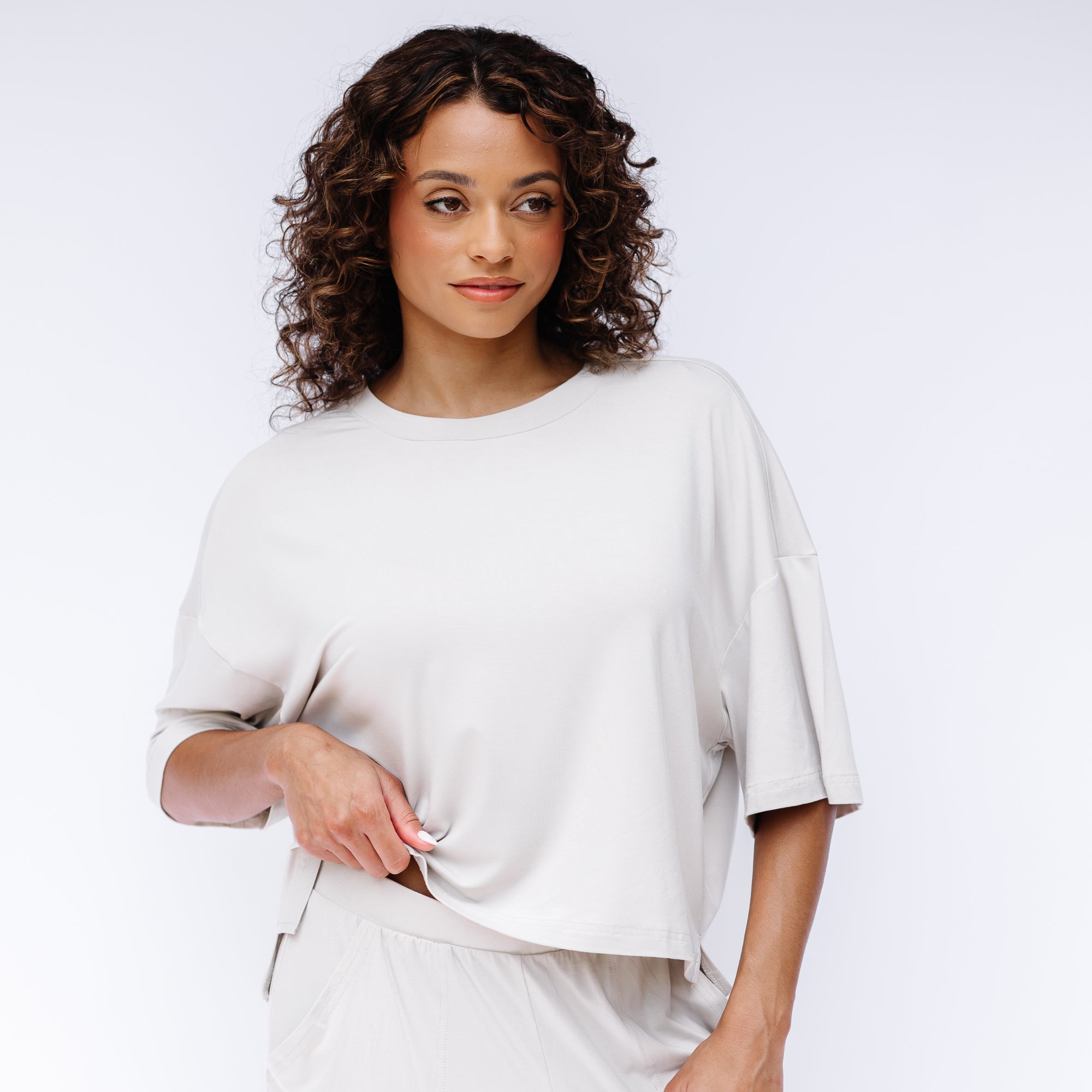 Female model standing in front of a white background wearing the Women's Short Sleeve Tee in Oat