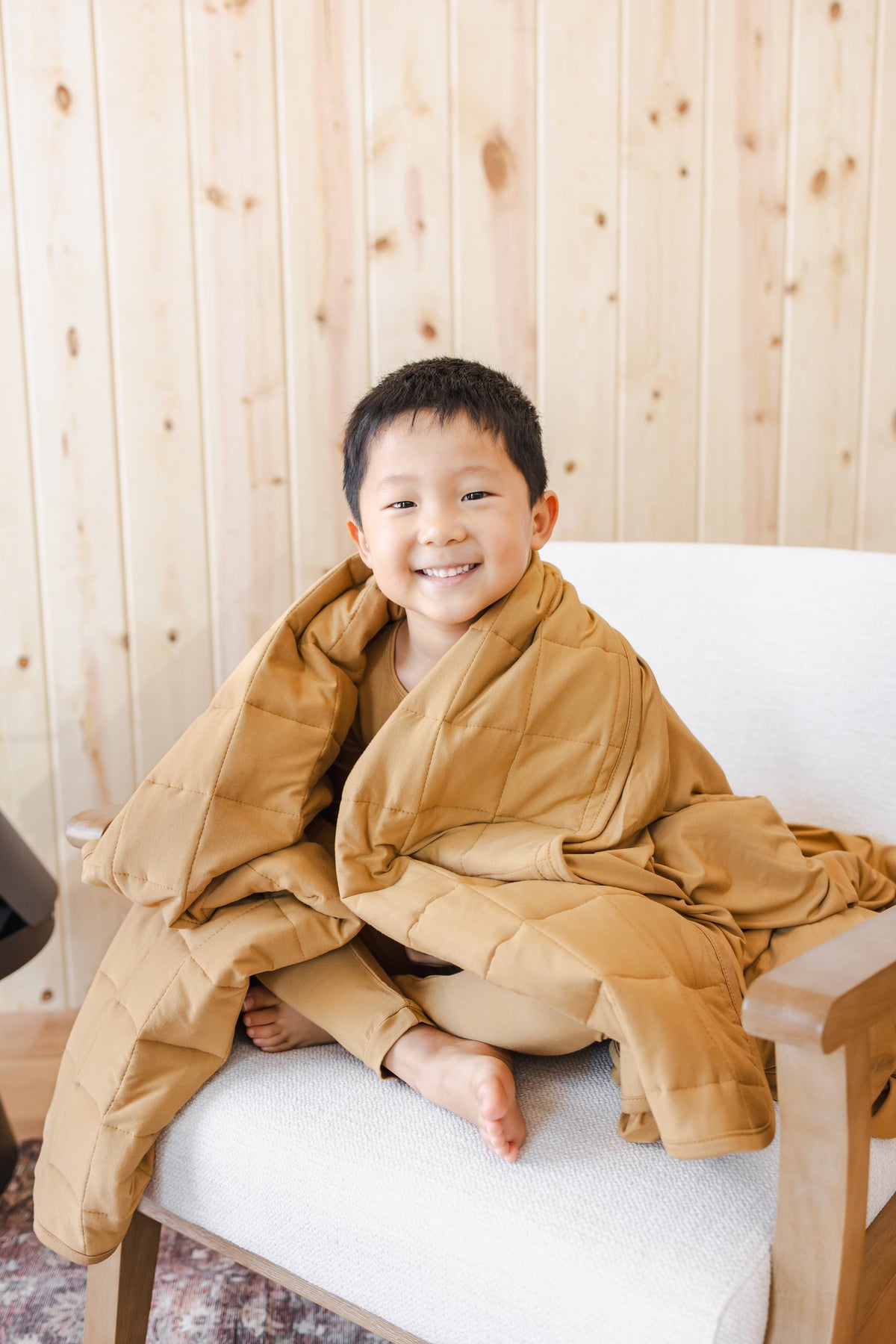 Child covered with Youth Blanket in Ochre 2.5 sitting on a sofa