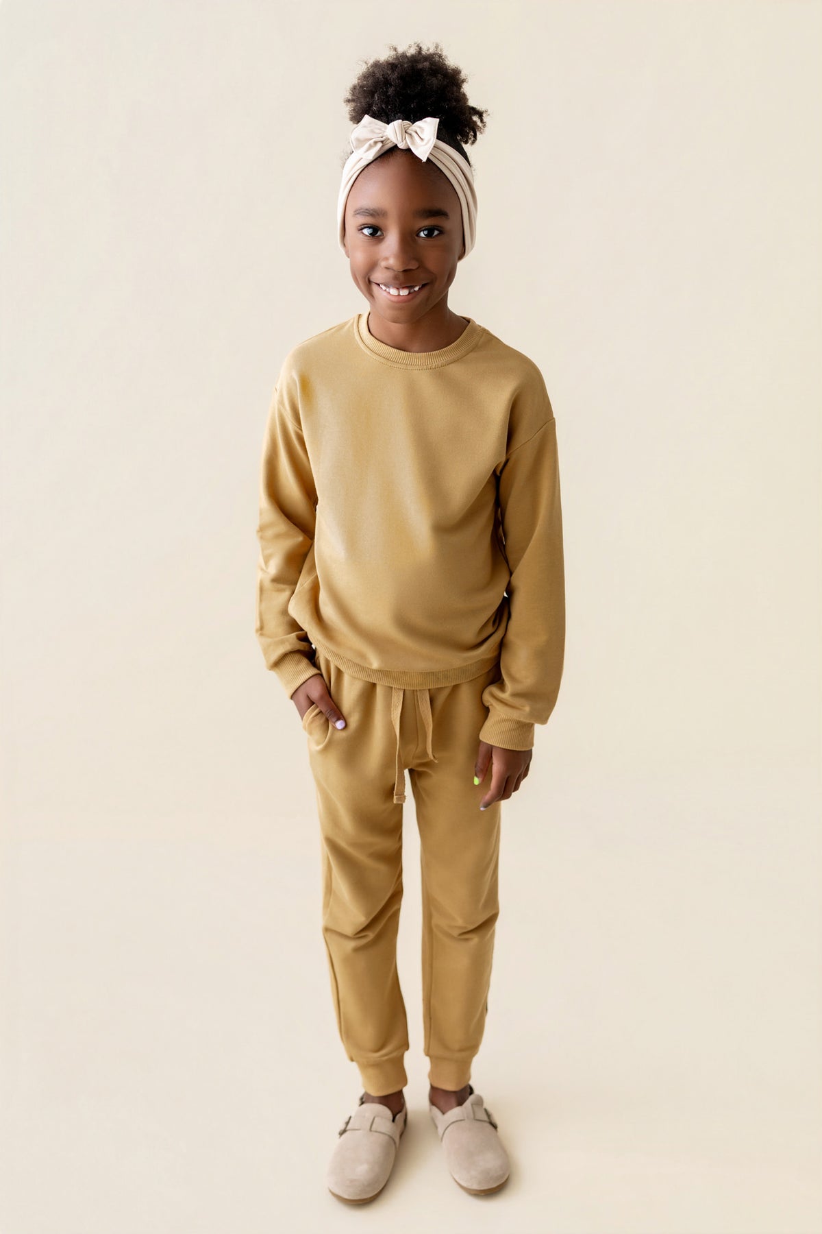 Girl wearing Jogger Pant in Ochre color under similar color sweatshirt on a beige background
