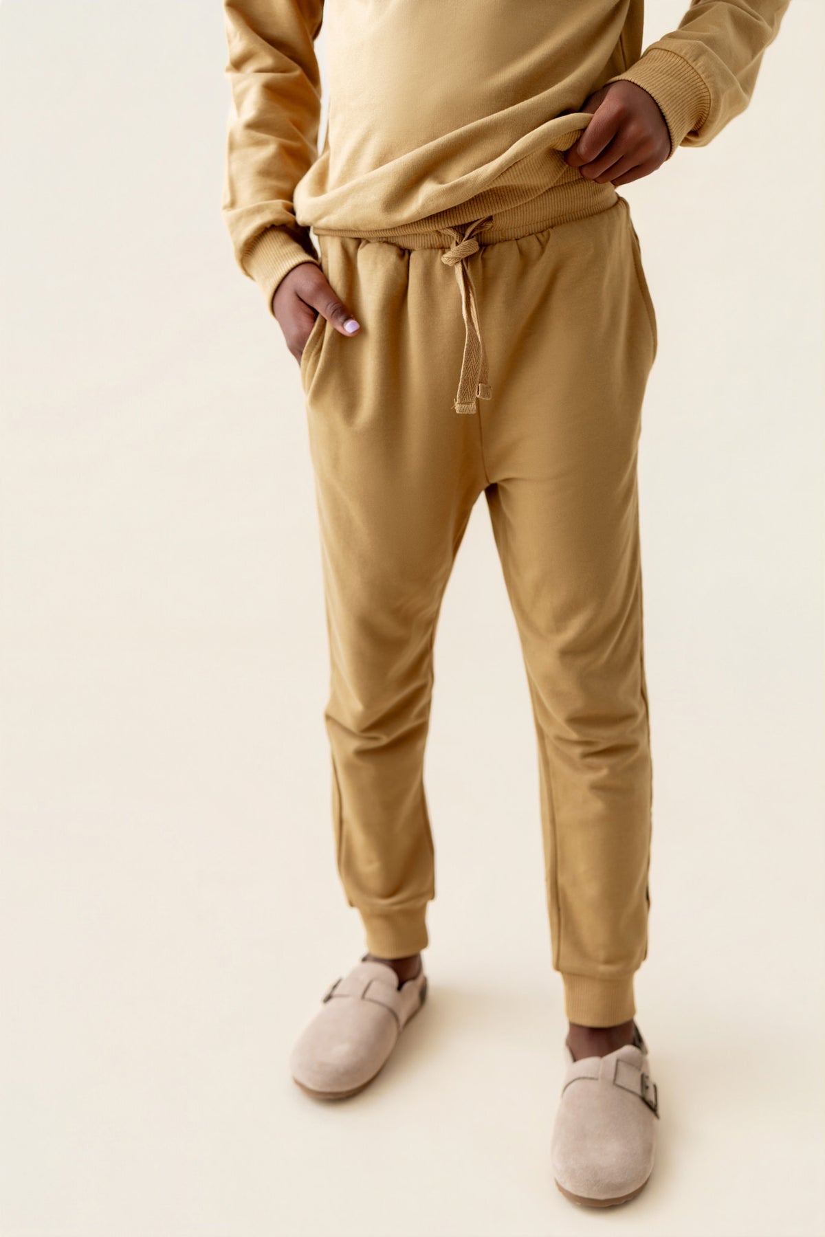 Modal wearing Jogger Pant in Ochre color under similar color sweatshirt on a beige background