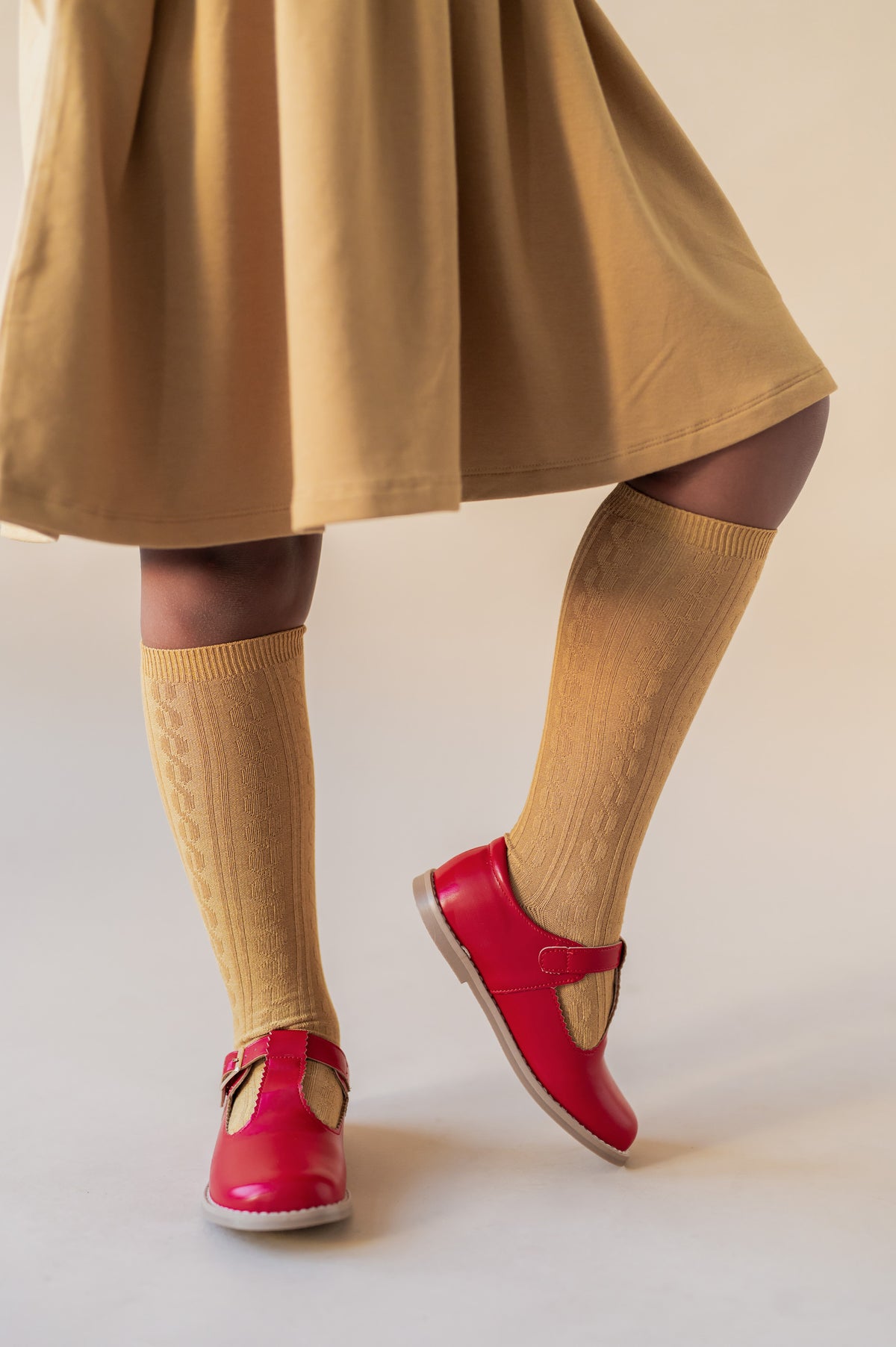 Modal wearing Knee High Socks in Ochre color with red shoes.