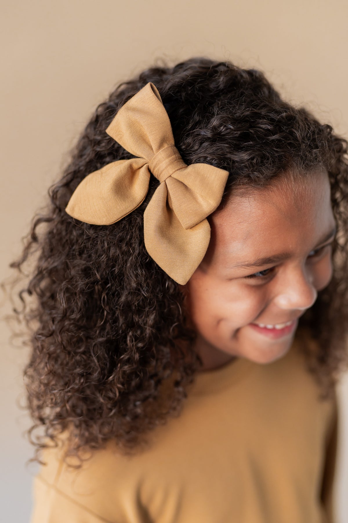 Modal wearing Medium Alligator Clip Bow in Ochre color in her hair.