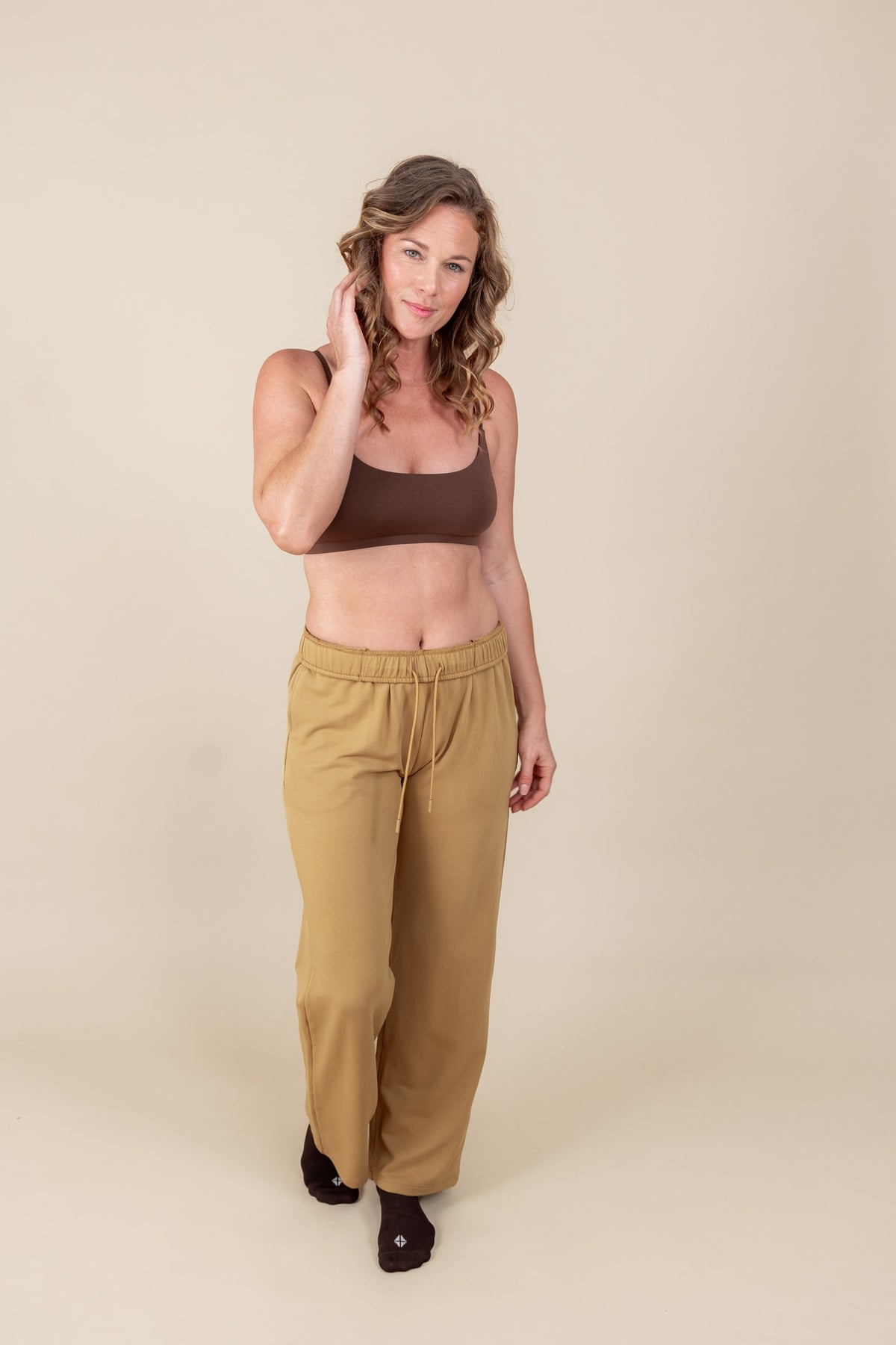 Modal wearing Women's Sweatpants in Ochre color under brown tank top on a white background