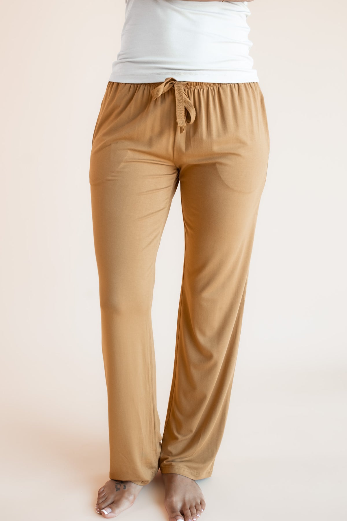 Model showcasing Women's Lounge Pants in Ochre under white camisole on a beige background