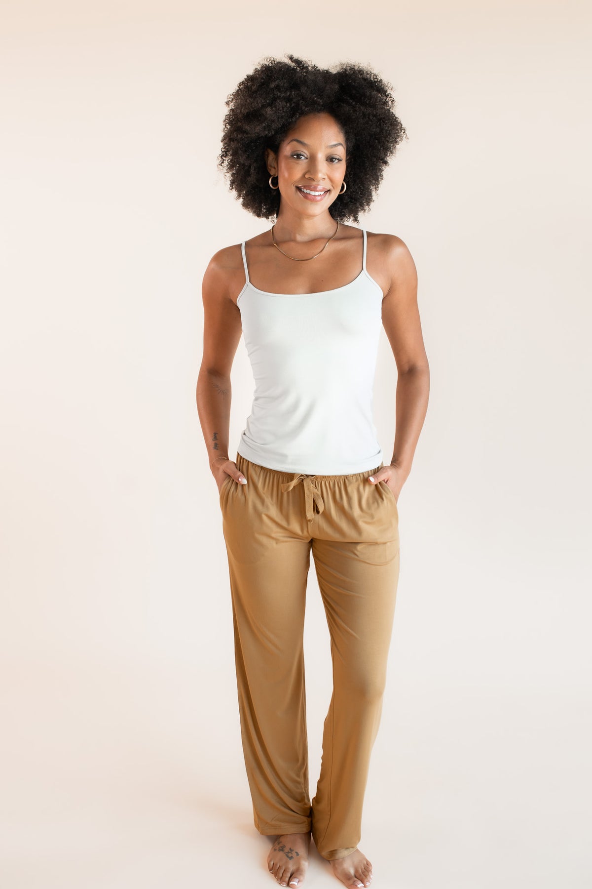 Model wearing Women's Lounge Pants in Ochre under white camisole on a beige background