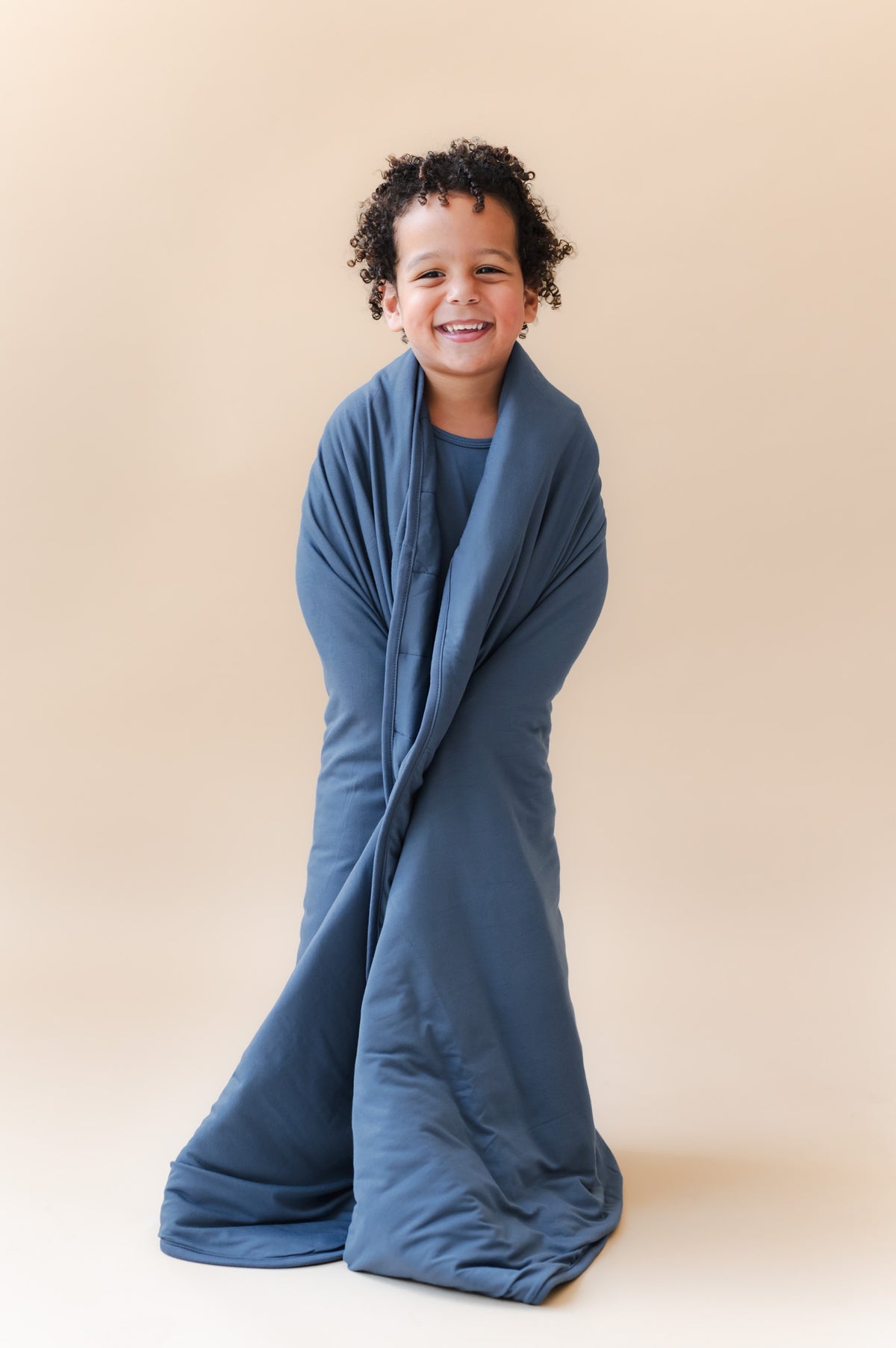 Boy wrapped in Youth Blanket in Oxford 2.5 on a beige background