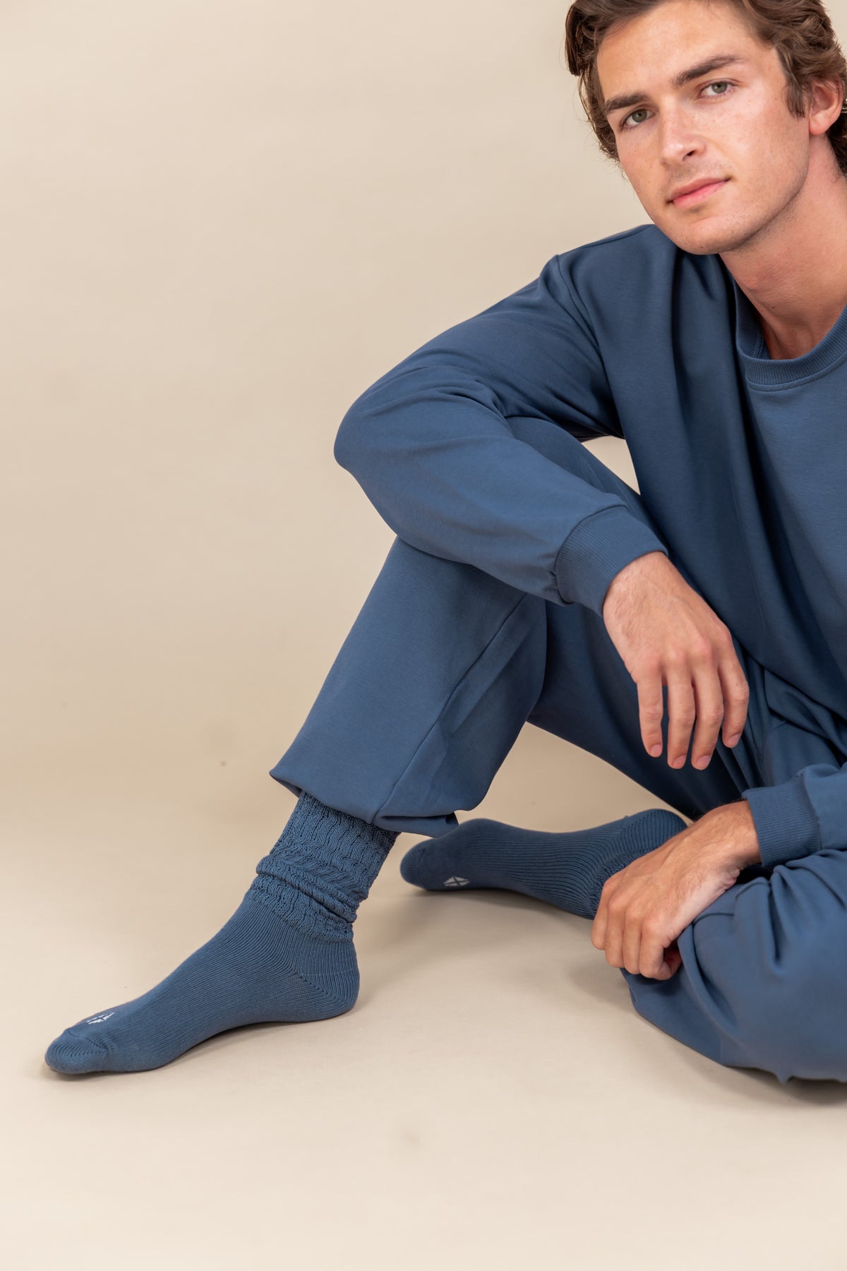 Modal sitting on floor wearing Adult Scrunch Socks in Oxford color while wearing oxford color jogger set on a beige background