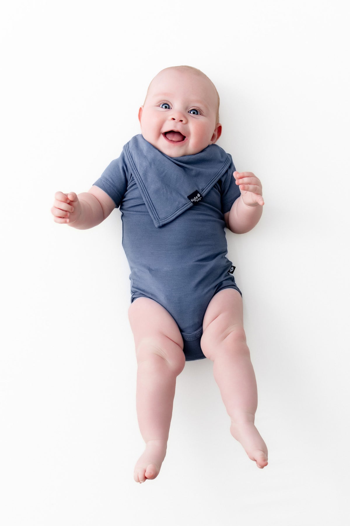 Baby smiling in Bib in Oxford over similar color bodysuit on a white background