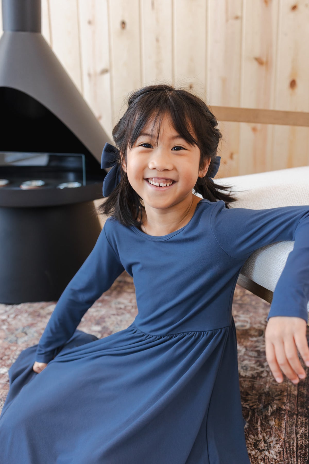 Girl wearing Long Sleeve Twirl Dress in Oxford sitting near chimney