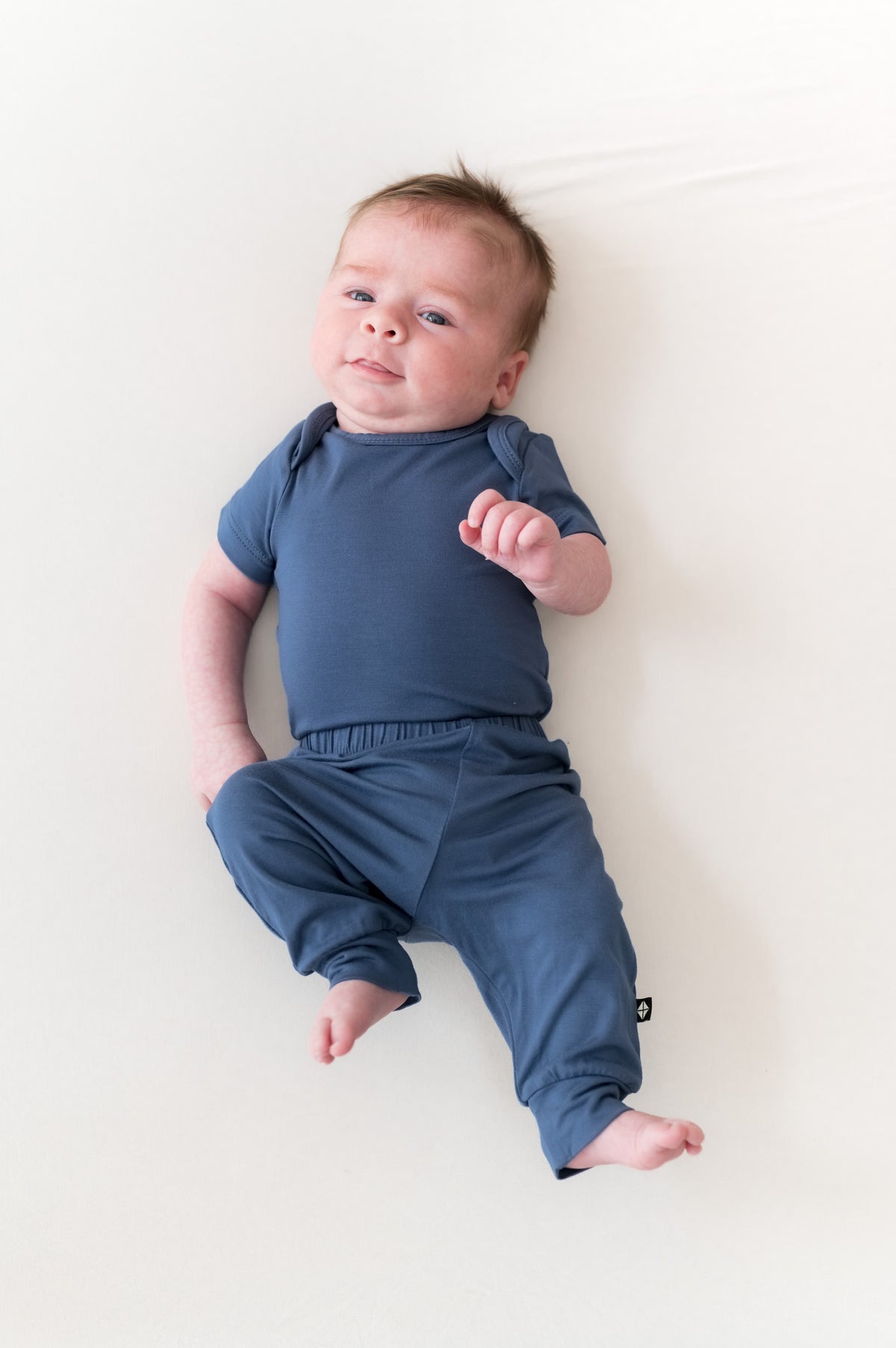 Baby wearing Pant in Oxford over similar color bodysuit on a beige background