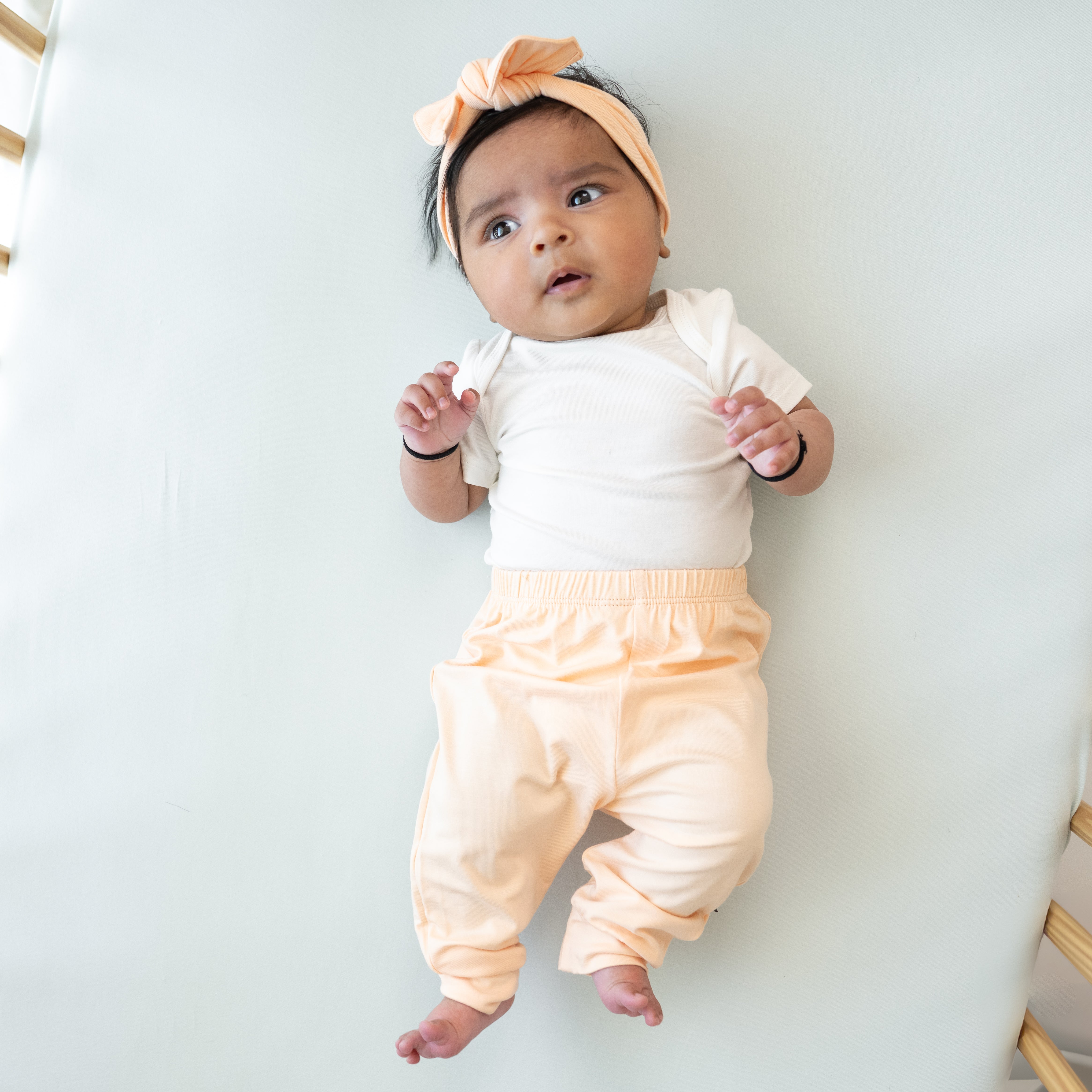 Infant model wearing the Knotted Bow Headband in Canyon paired with a Cloud Bodysuit and pants in Canyon