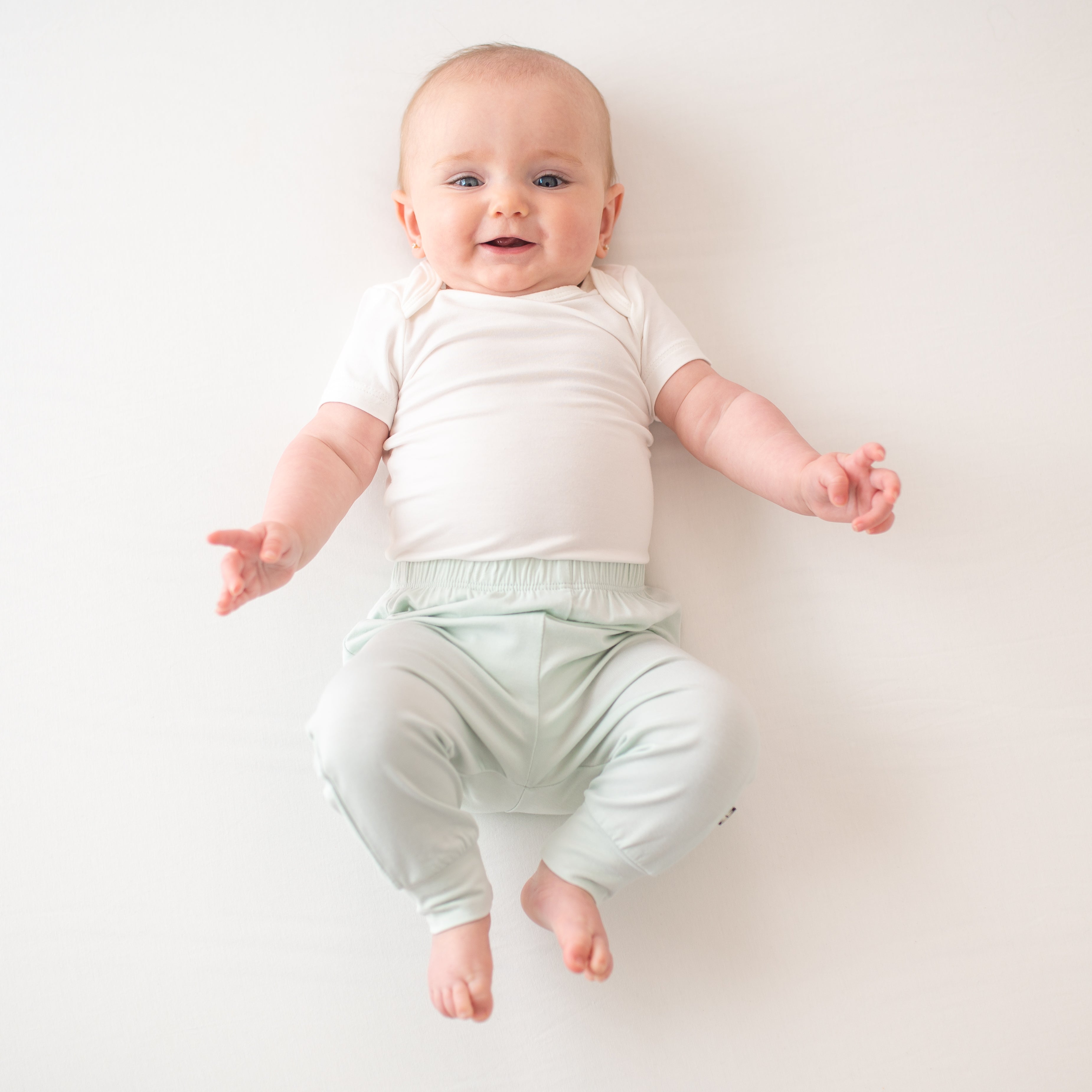 Infant model laying down wearing the Pant in Dew paired with a Cloud Bodysuit