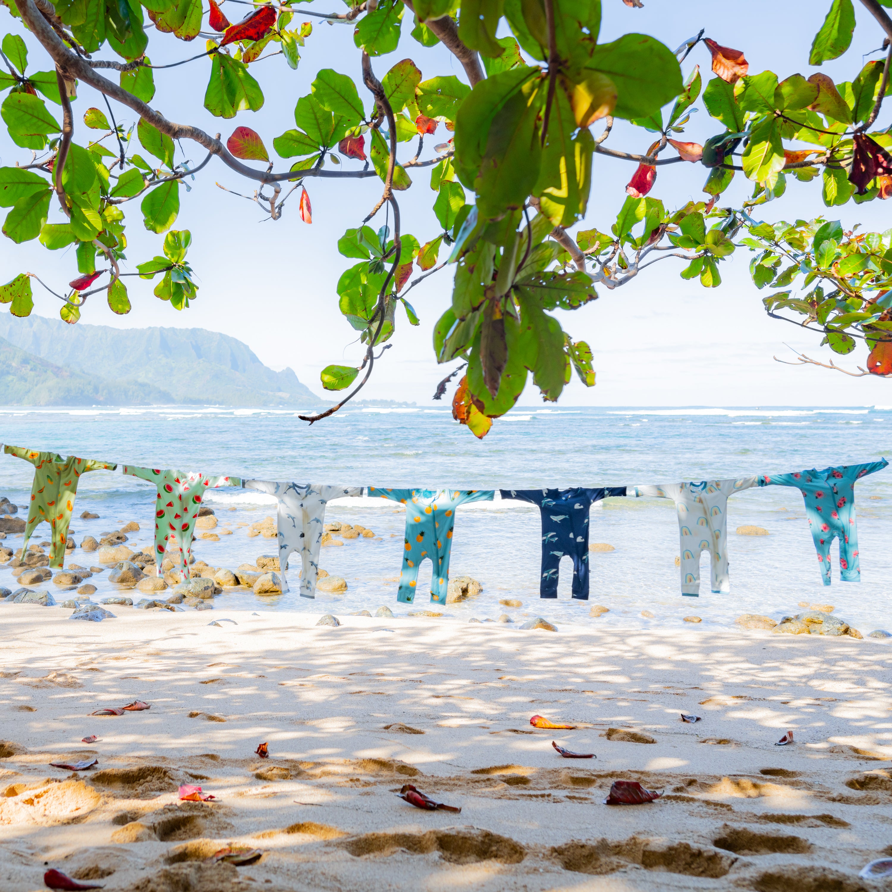 A clothesline showing zippered rompers from kyte baby spring and summer collection in front of ocean