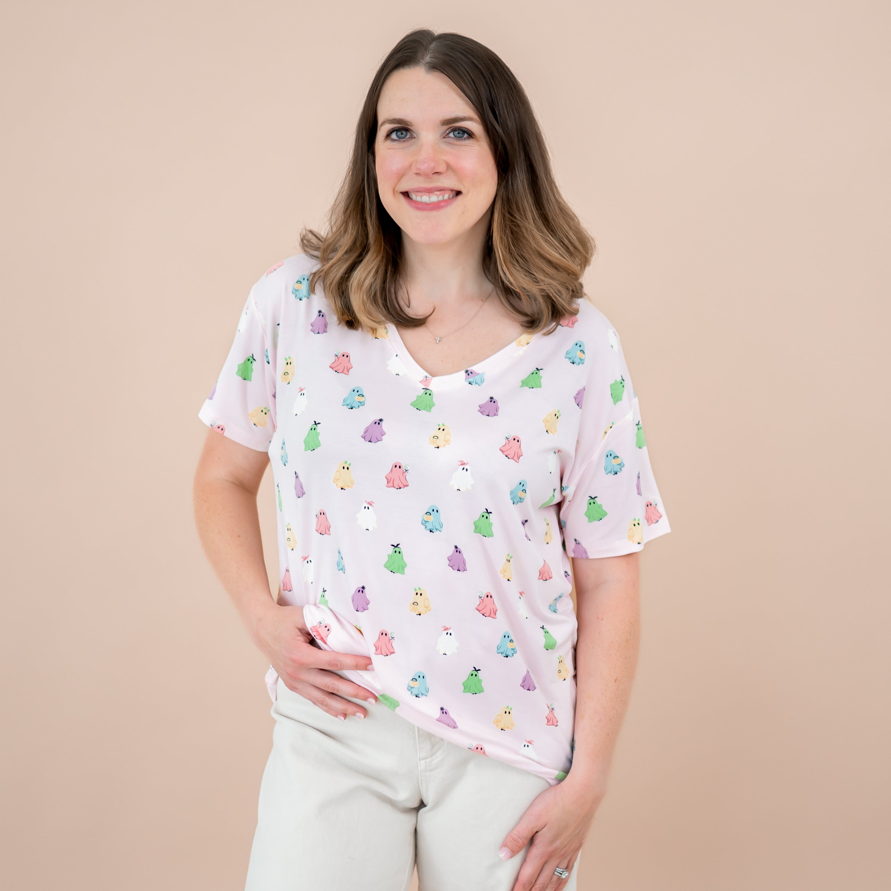 Smiling female model wearing the Women's Relaxed Fit V-Neck in Pastel Ghost with one hand at the waist of her cream wash jeans