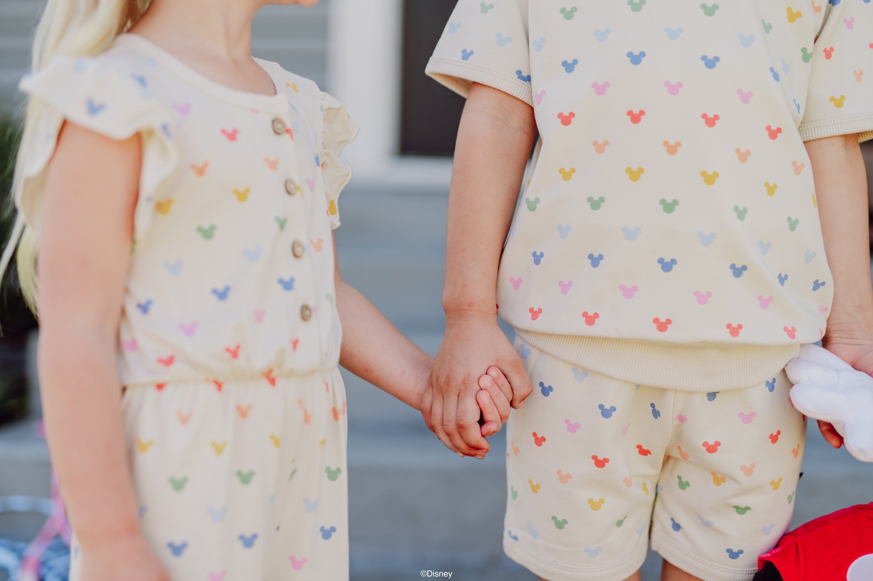 2 children holding hands wearing mickey mouse head printed bamboo apparel from kyte's collaboration with disney
