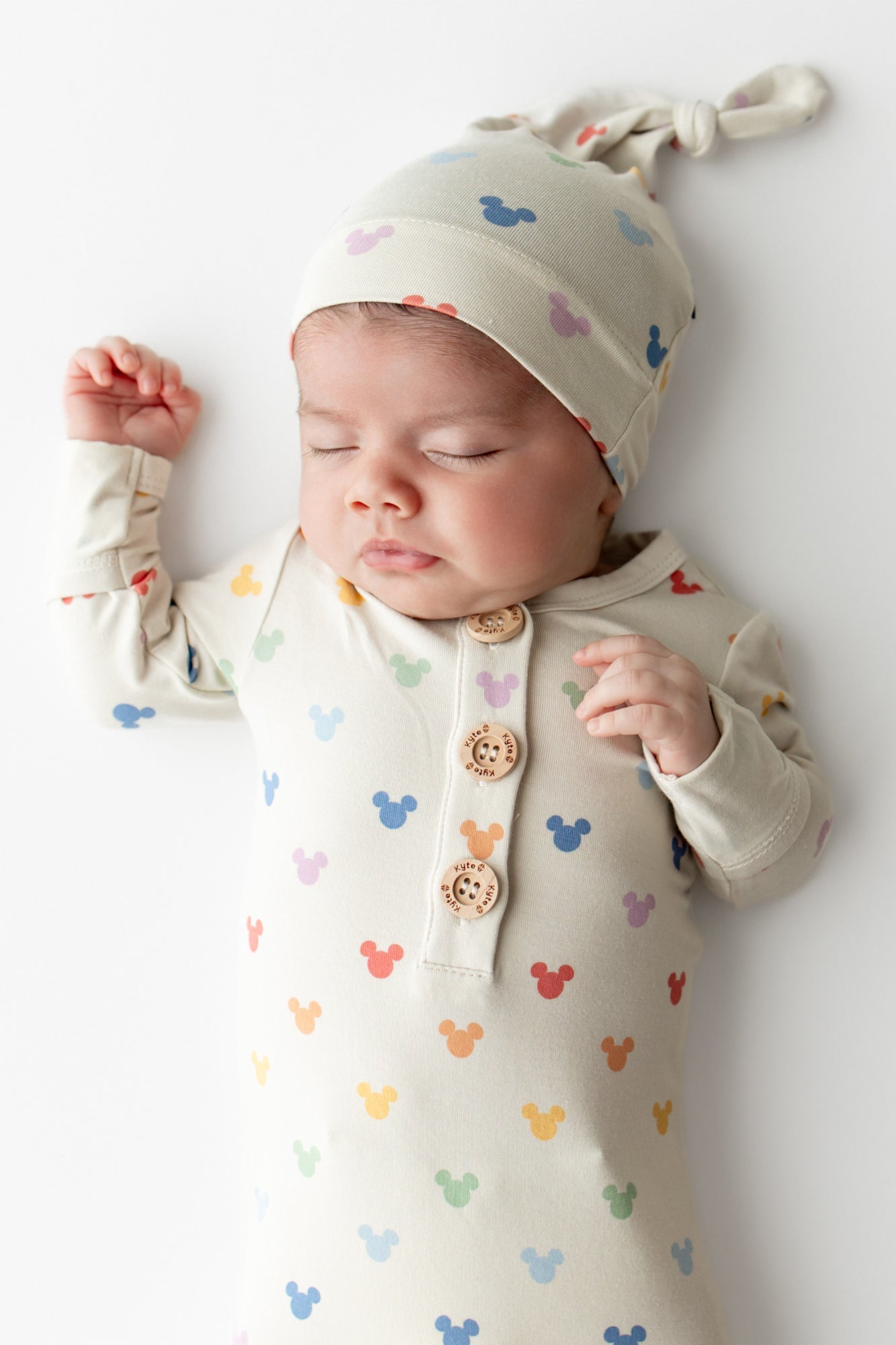 Baby wearing a hat and knotted gown with a Mickey head pattern