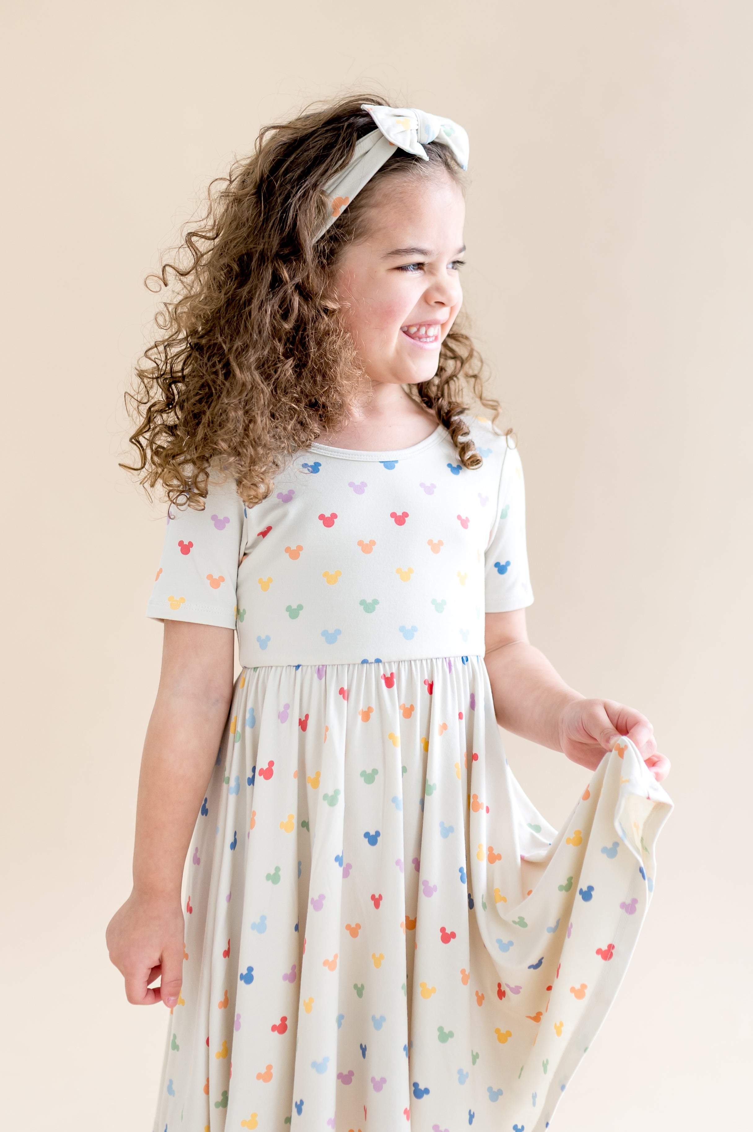 Girl in a twirl dress with colorful mickey mouse head pattern