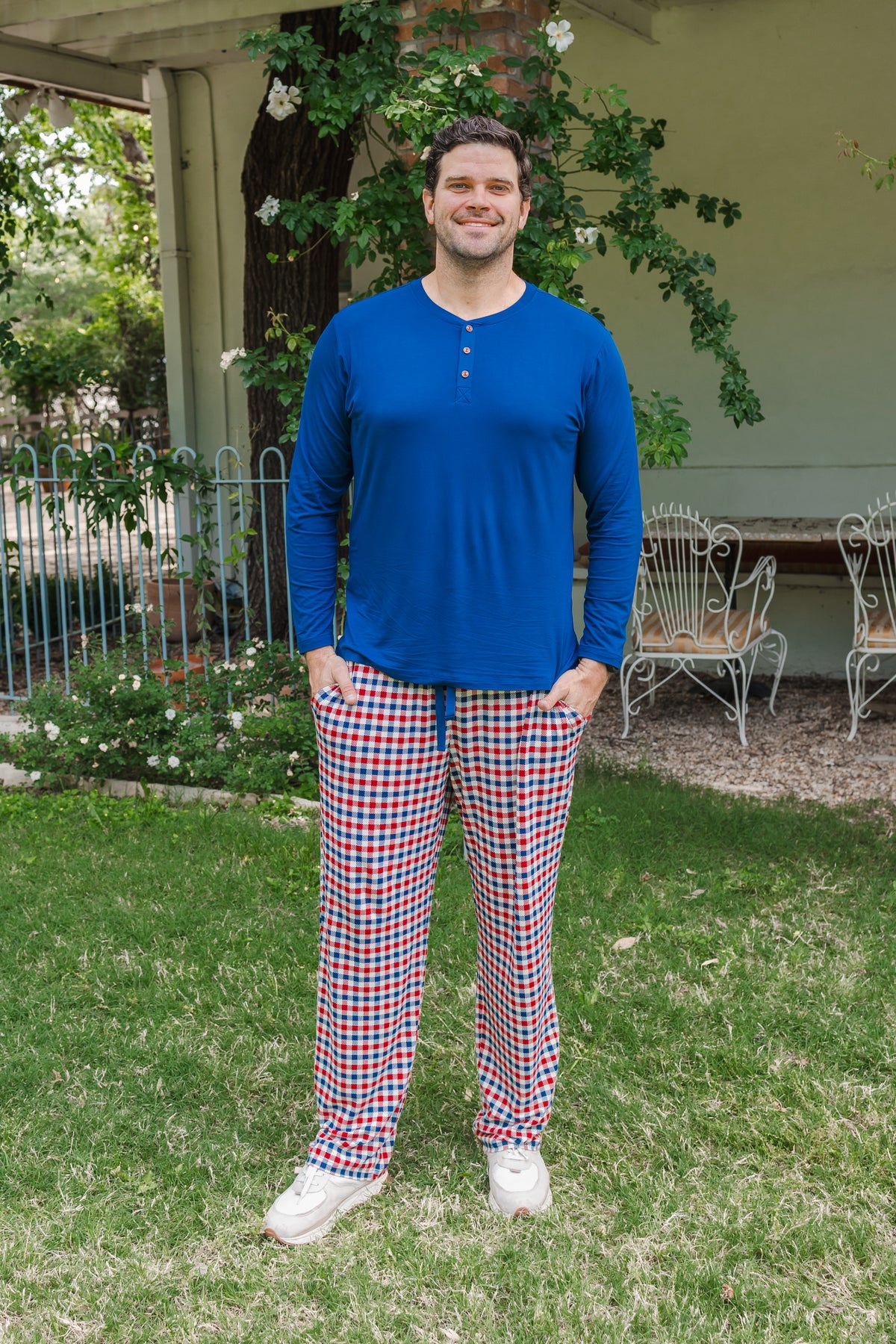 Man standing outdoors wearing a red blue and white Patriotic Gingham check print Men's lounge pant under Men's Long Sleeve Henley Top in Tahoe