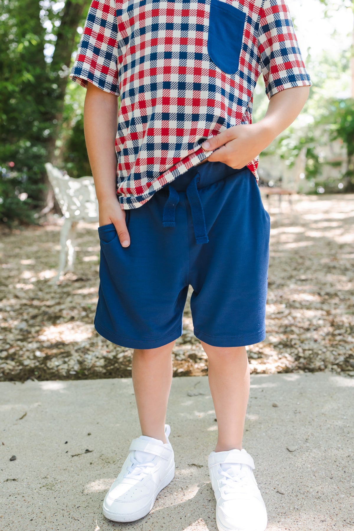 Toddler wearing Drawstring Short in Tahoe under red blue and white gingham tee with white shoes outdoors