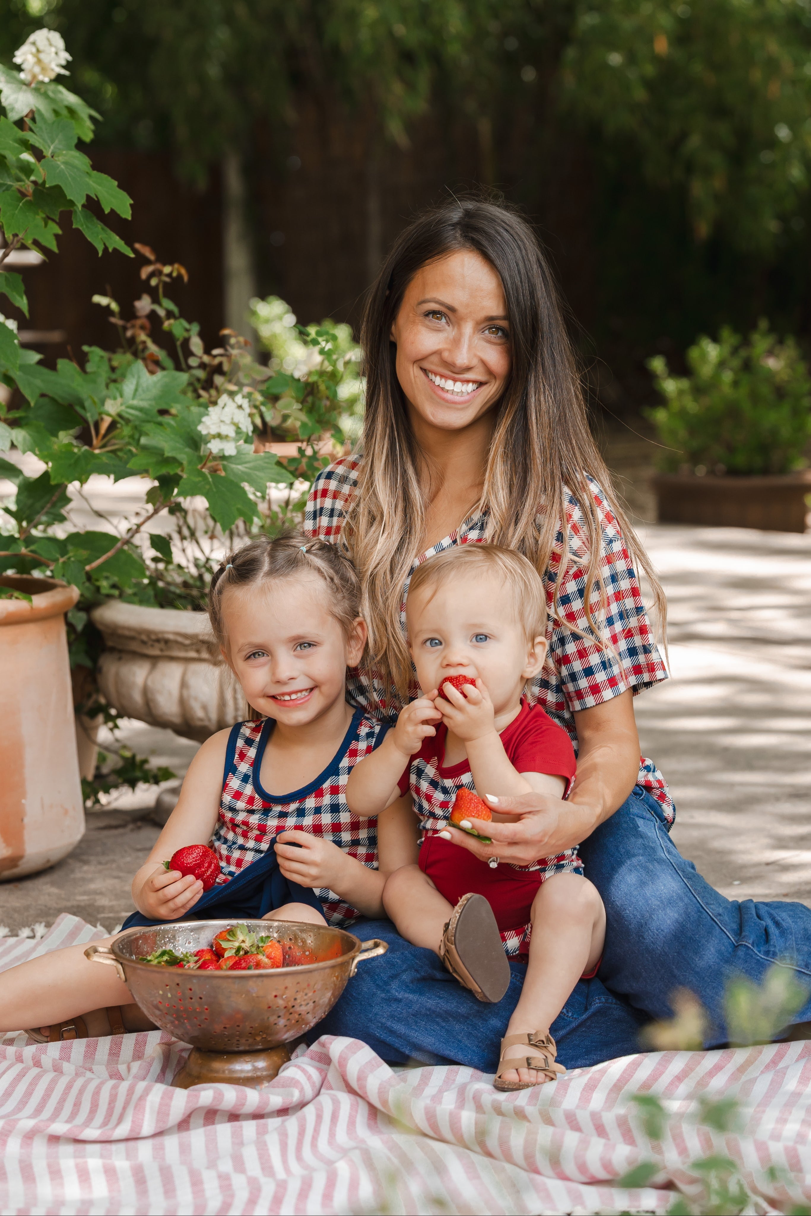 family of 3 wearing matching patriotic red white and blue gingham outfits