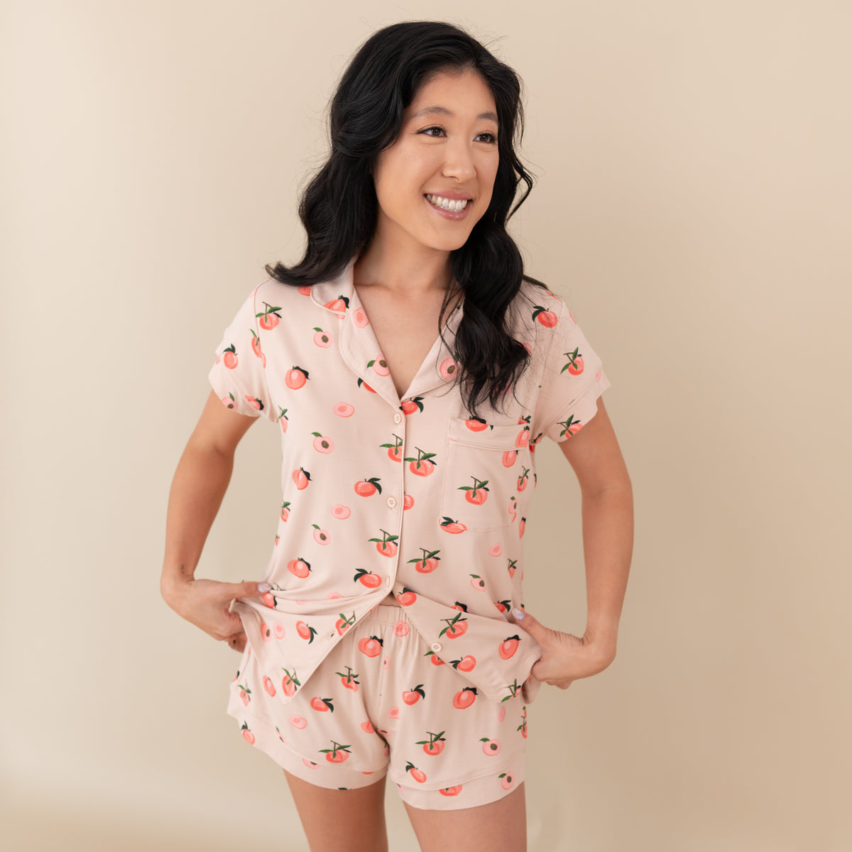Woman modeling Women’s Short Sleeve Pajama Set in Peach slightly pulling at pajama top
