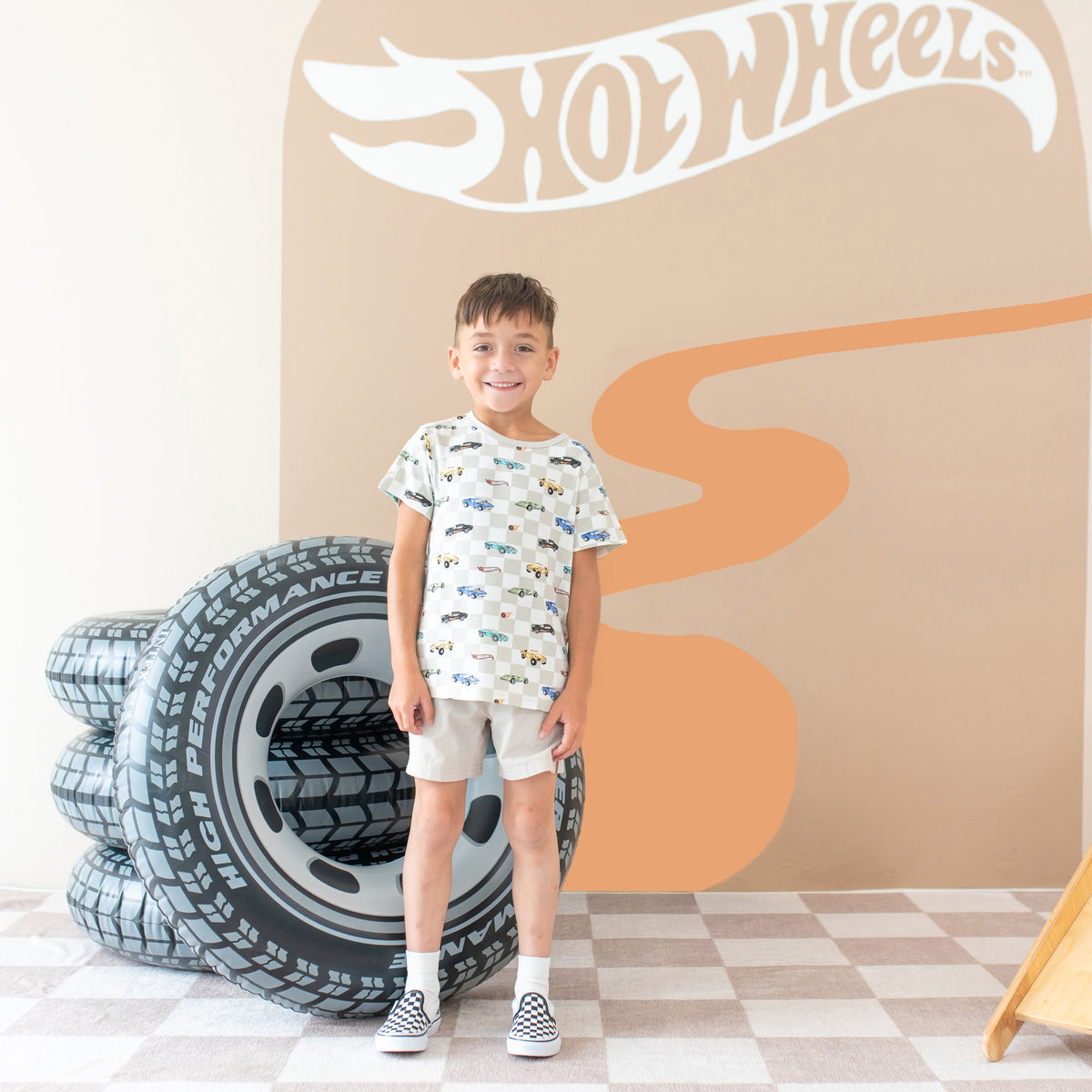 Smiling child wearing the Sleep Bag Walker in Fast and Fierce 1.0 standing in front of a Hot Wheels™ back drop