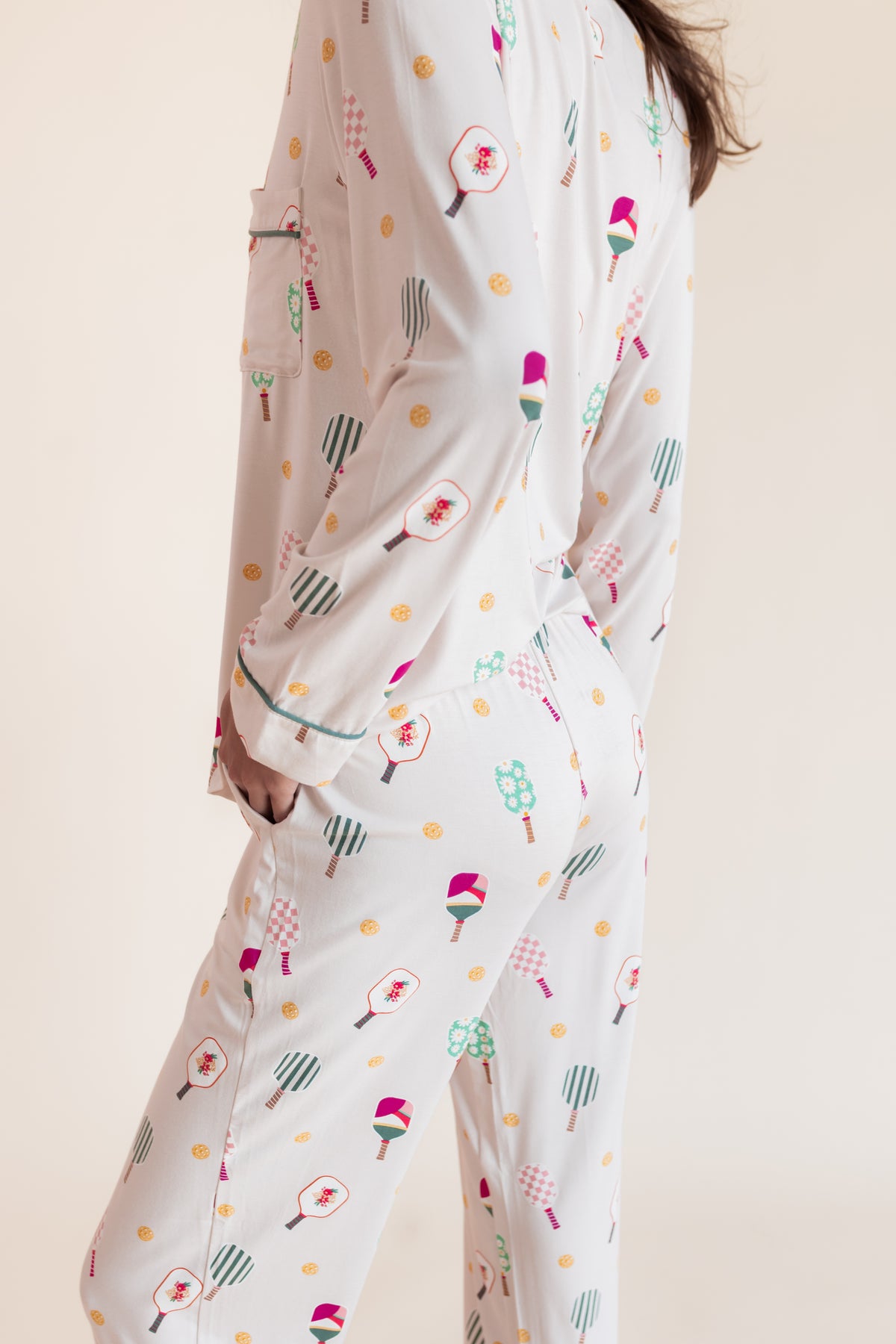 A person wearing a matching long-sleeve pajama set with a playful pickleball print, shown from the back against a plain beige studio background.