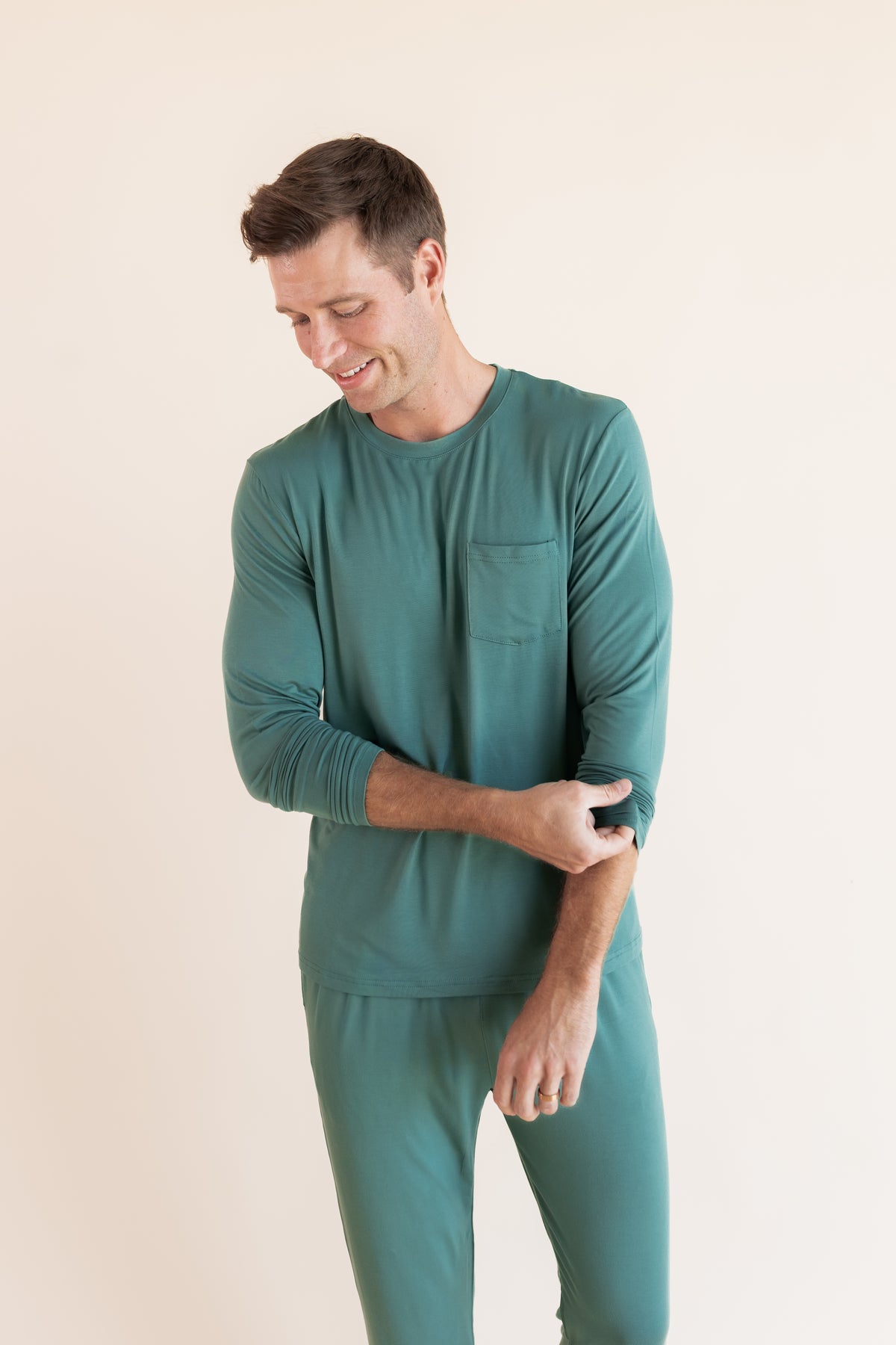Close up of Model wearing Men's Jogger Set in Pine on a beige background