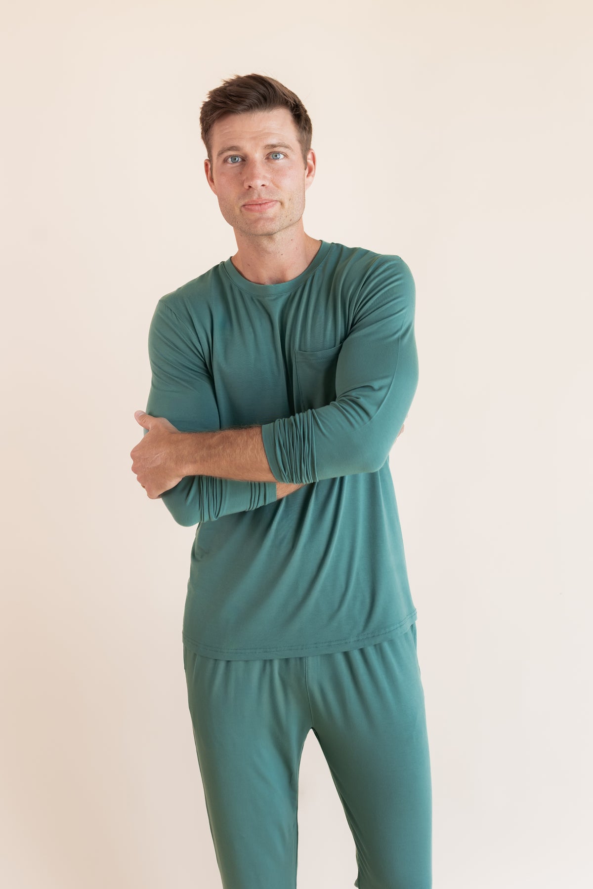 Model wearing Men's Jogger Set in Pine with folded hands on a beige background