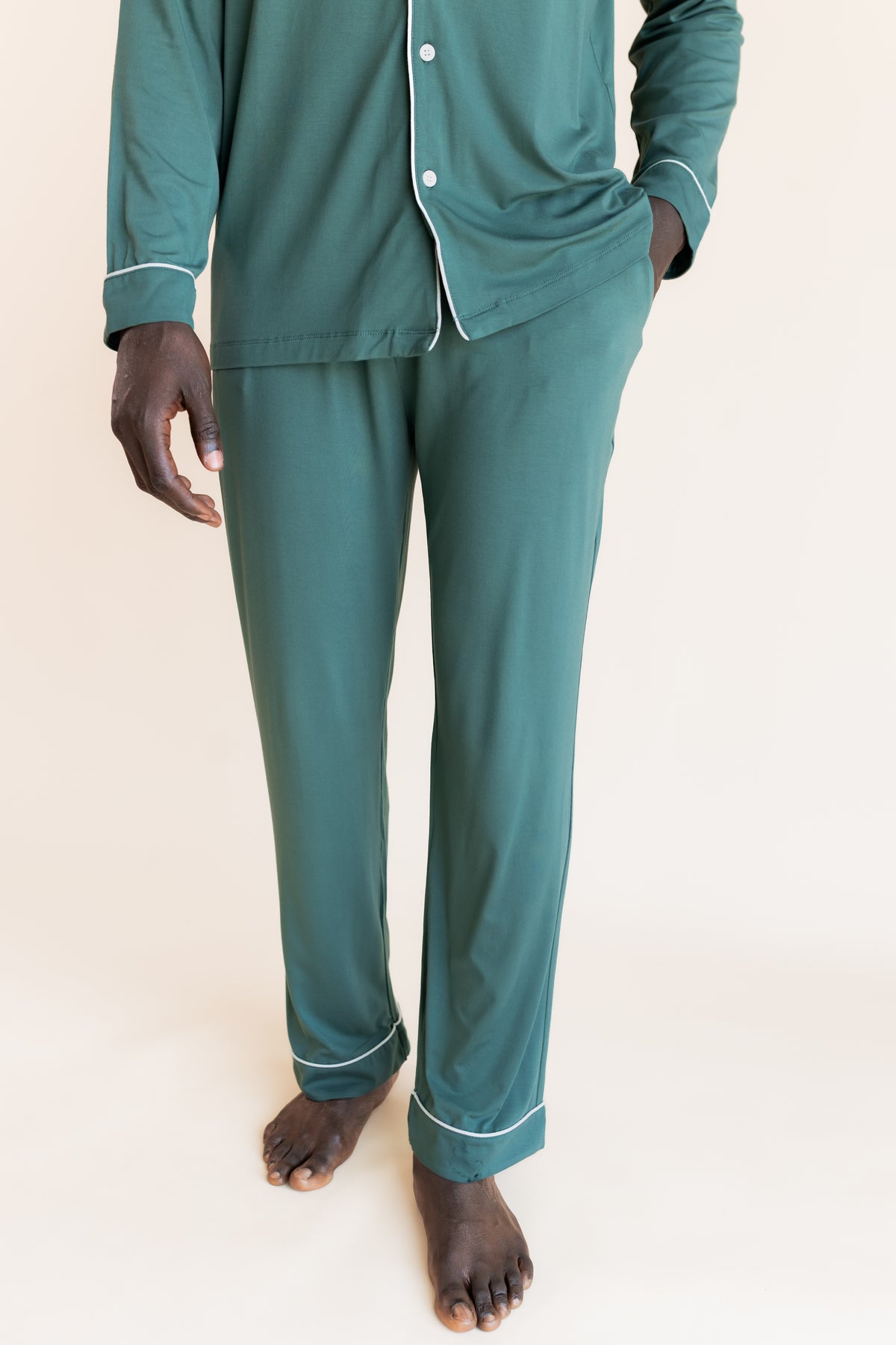 Model wearing Men's Long Sleeve Pajama Set in Pine with pockets on a beige background