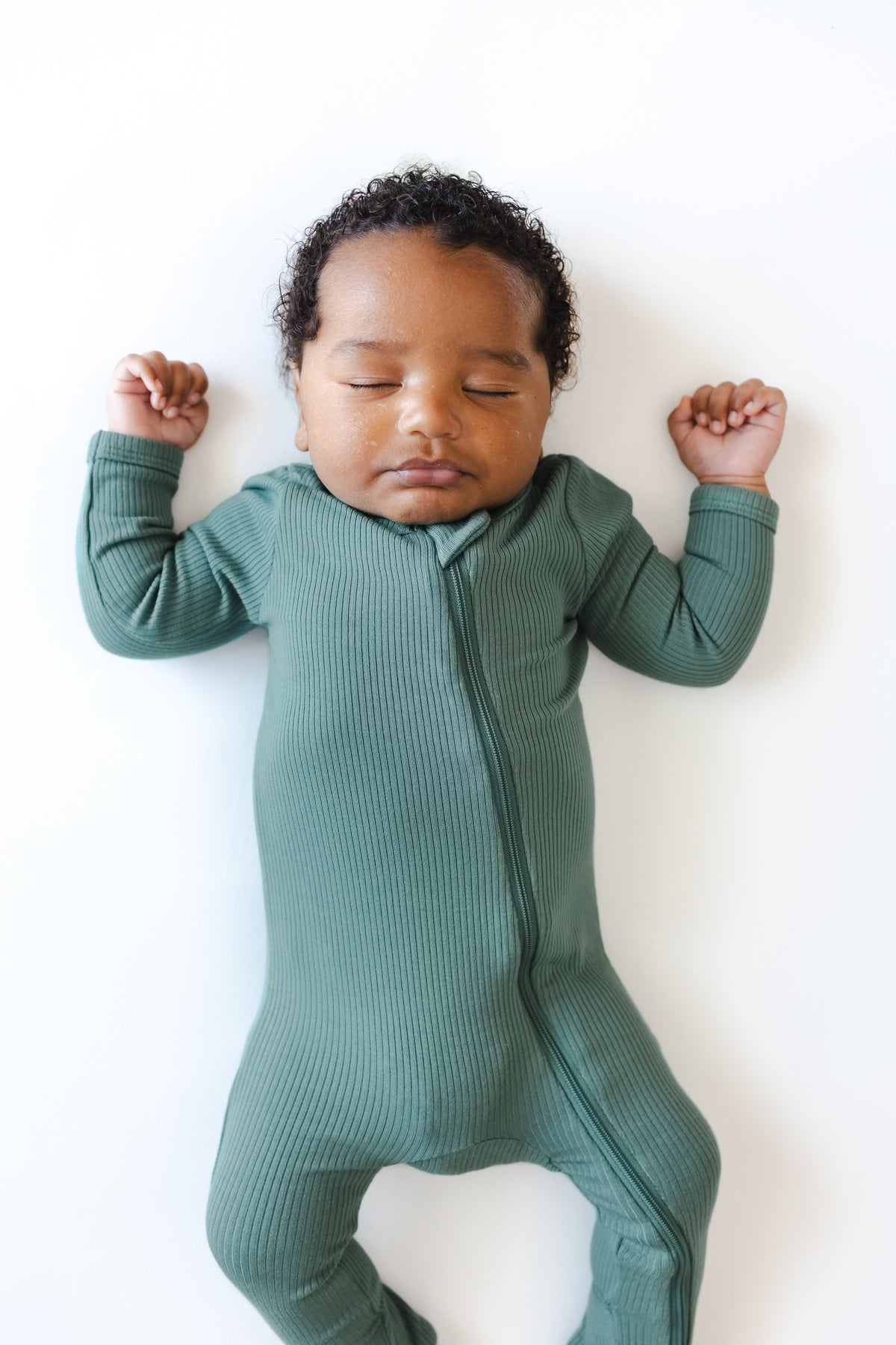 Close up of Baby sleeping in Ribbed Zipper Footie in Pine on a white background